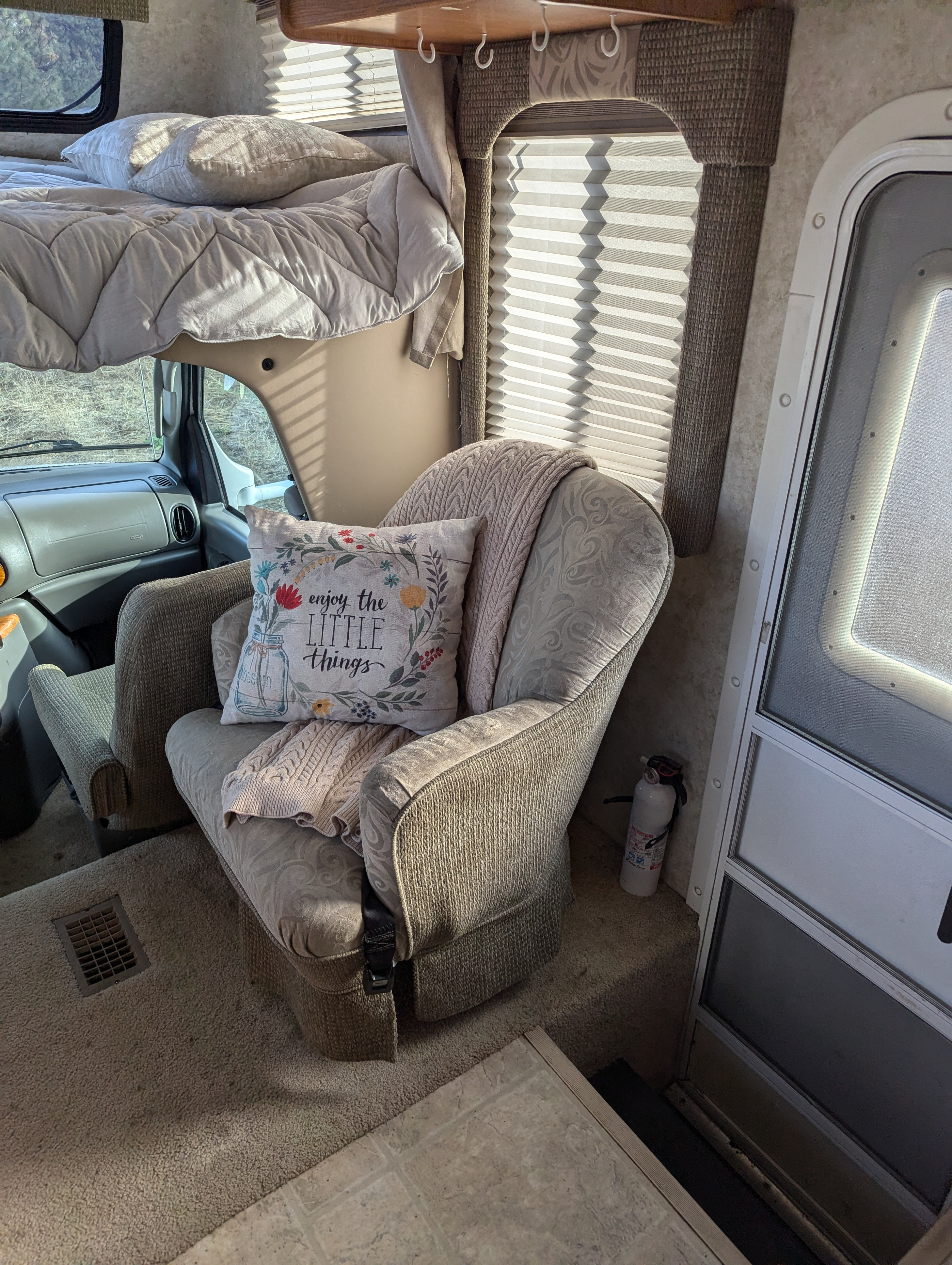 Cozy RV rental interior featuring an armchair, blanket, "enjoy the little things" pillow, and overhead bed.. Four Winds 5000 2005