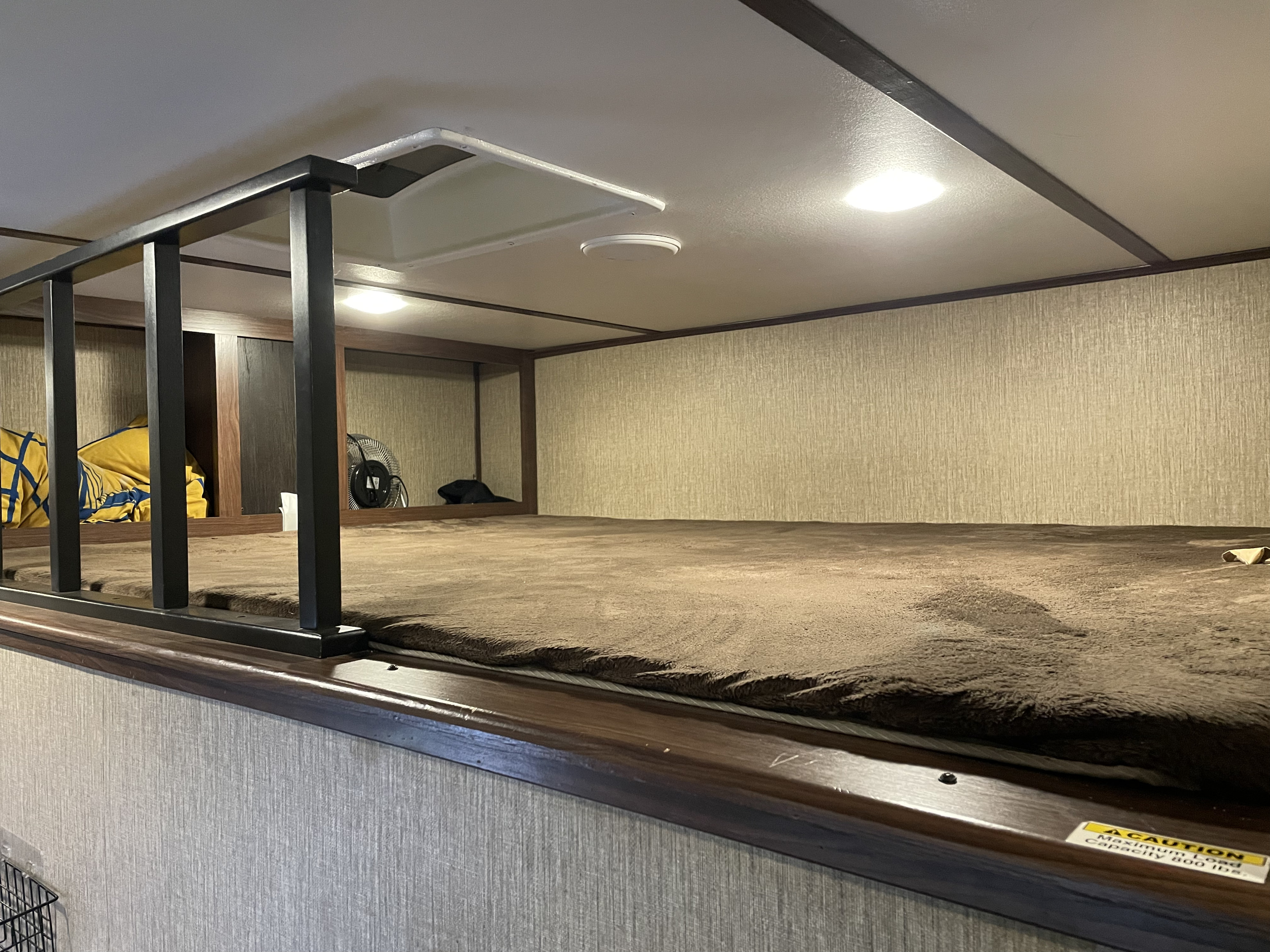 RV rental bunk bed shows a brown mattress, black safety rail, ceiling vent, and light. Designed for compact living.. Keystone RV Sprinter 2017