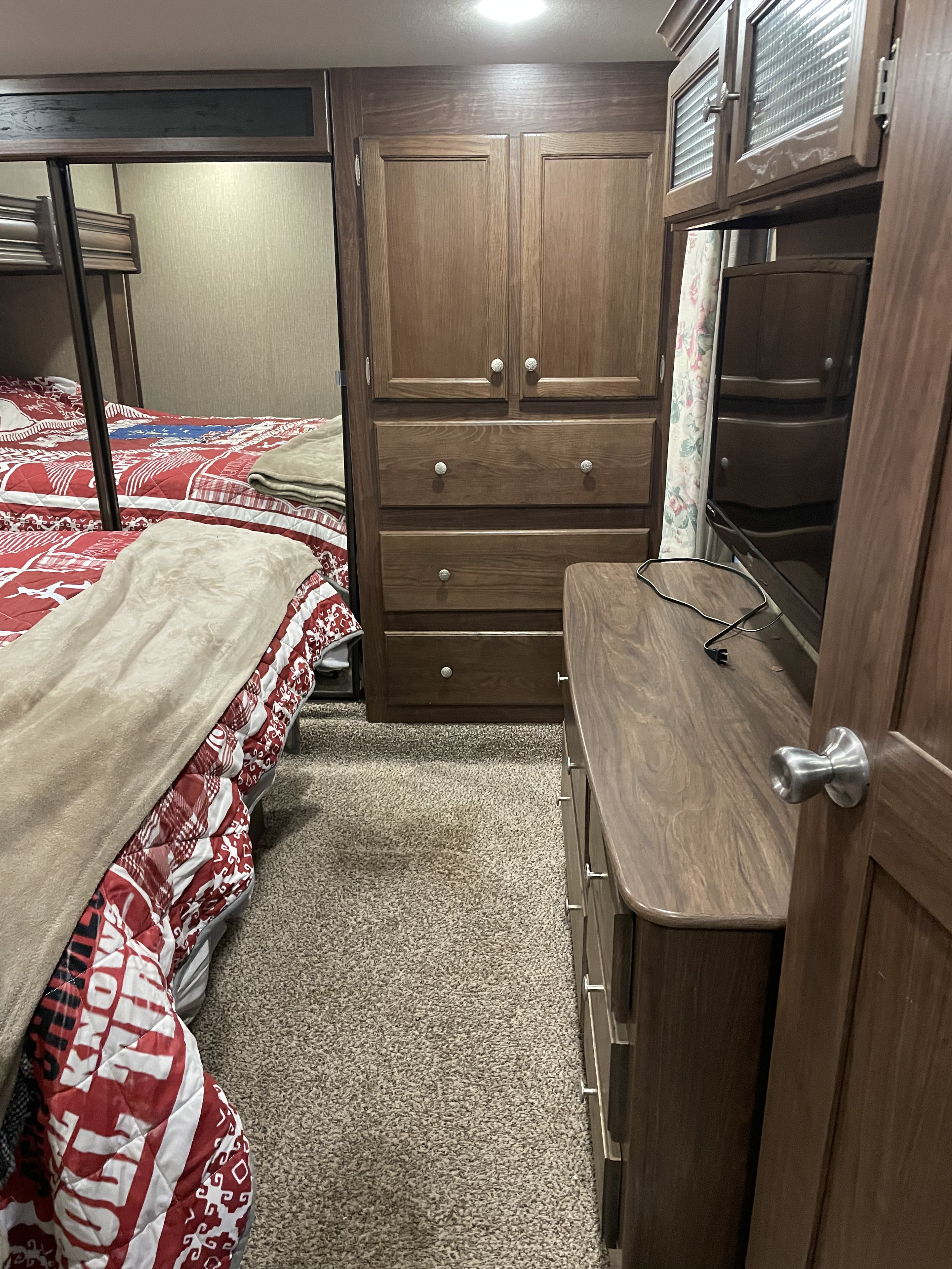 Inside an RV rental, a compact bedroom with bunk beds, wooden wardrobe/dresser, and a TV on a matching console.. Keystone RV Sprinter 2017
