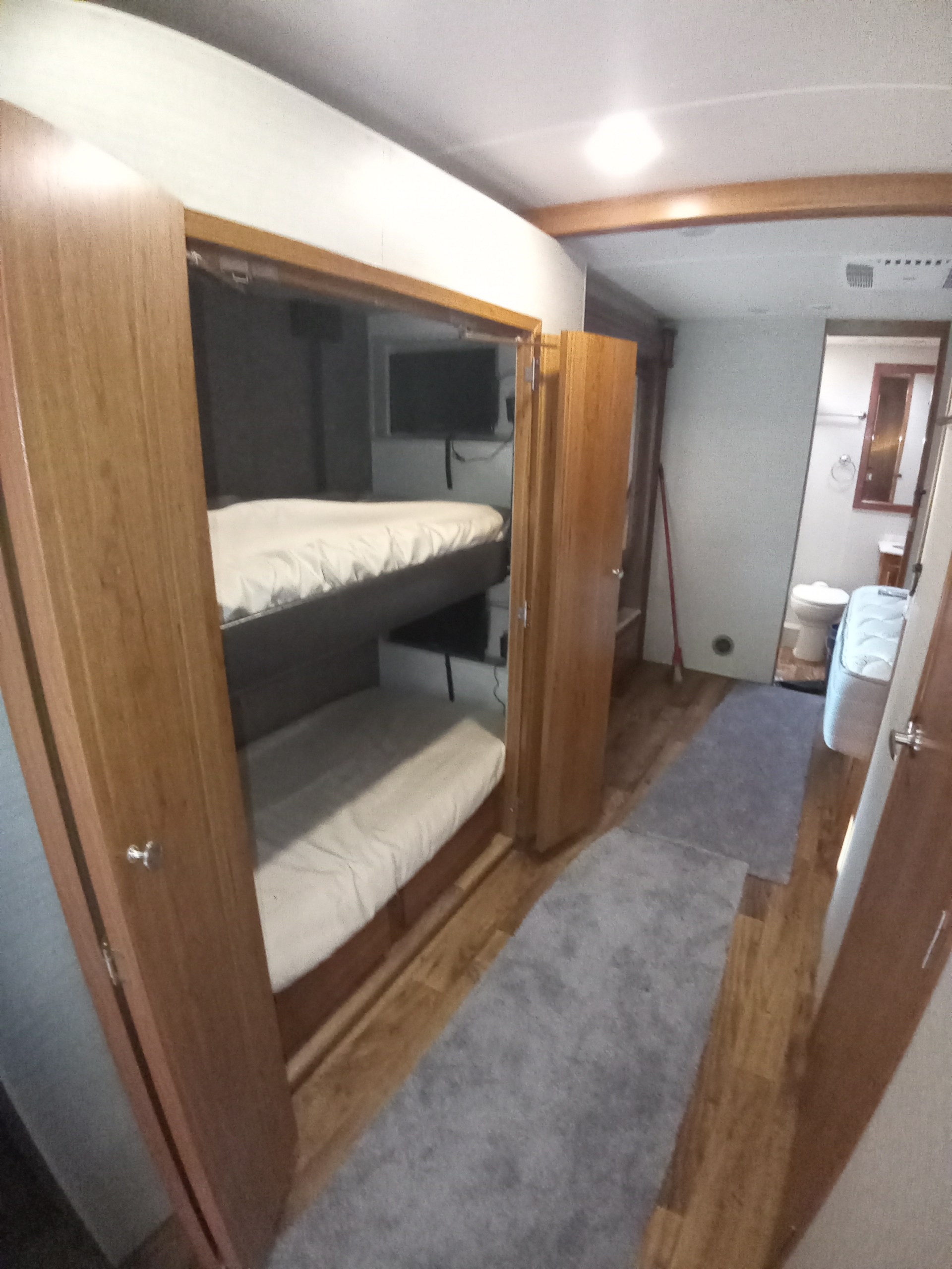 RV rental interior featuring cozy bunk beds with TVs, and a compact bathroom visible down the hallway.. Jayco Precept 2017