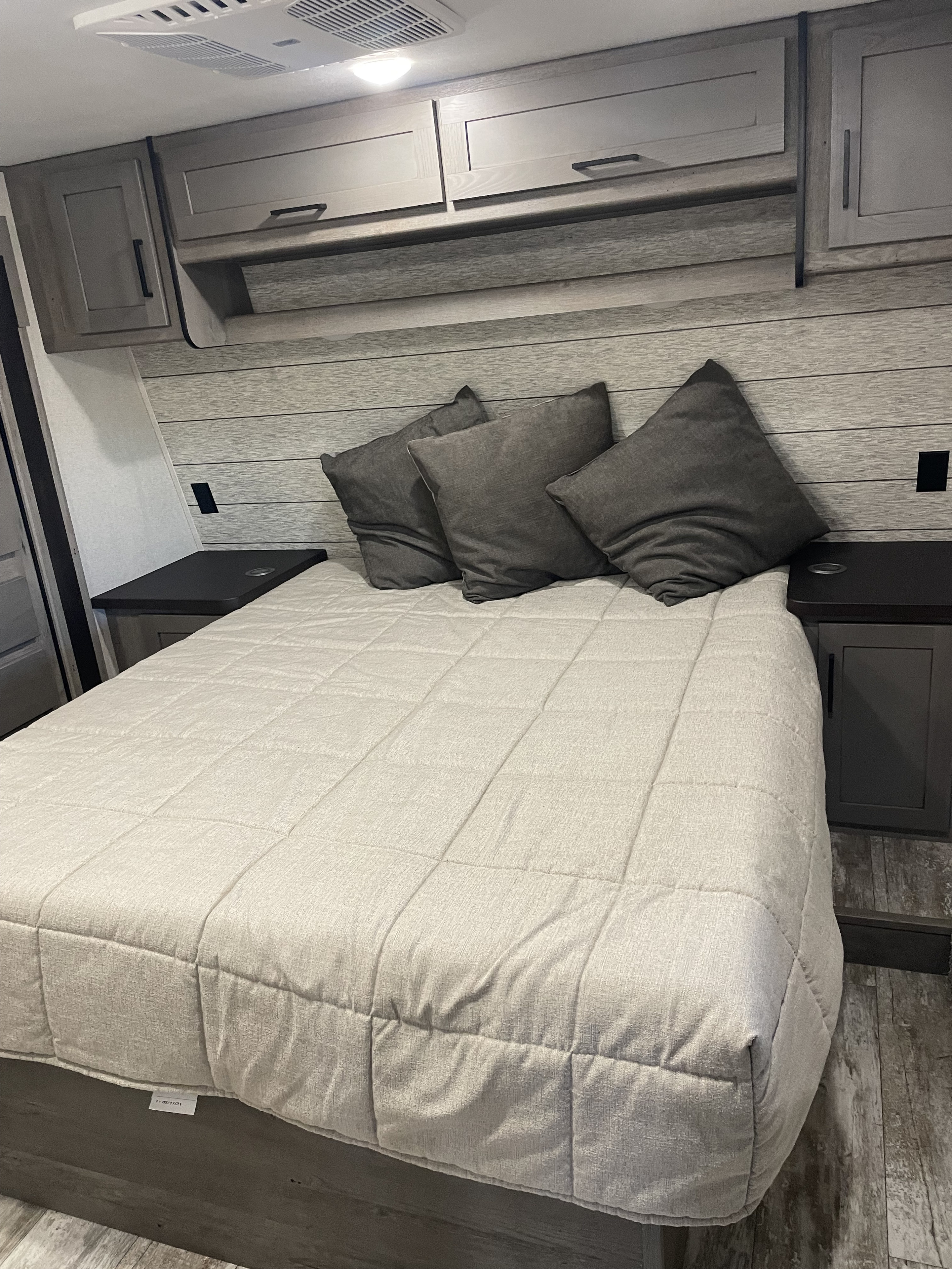 Relax in this RV rental bedroom featuring a comfortable bed, stylish overhead cabinets, and convenient side tables.. Keystone Carbon 2021