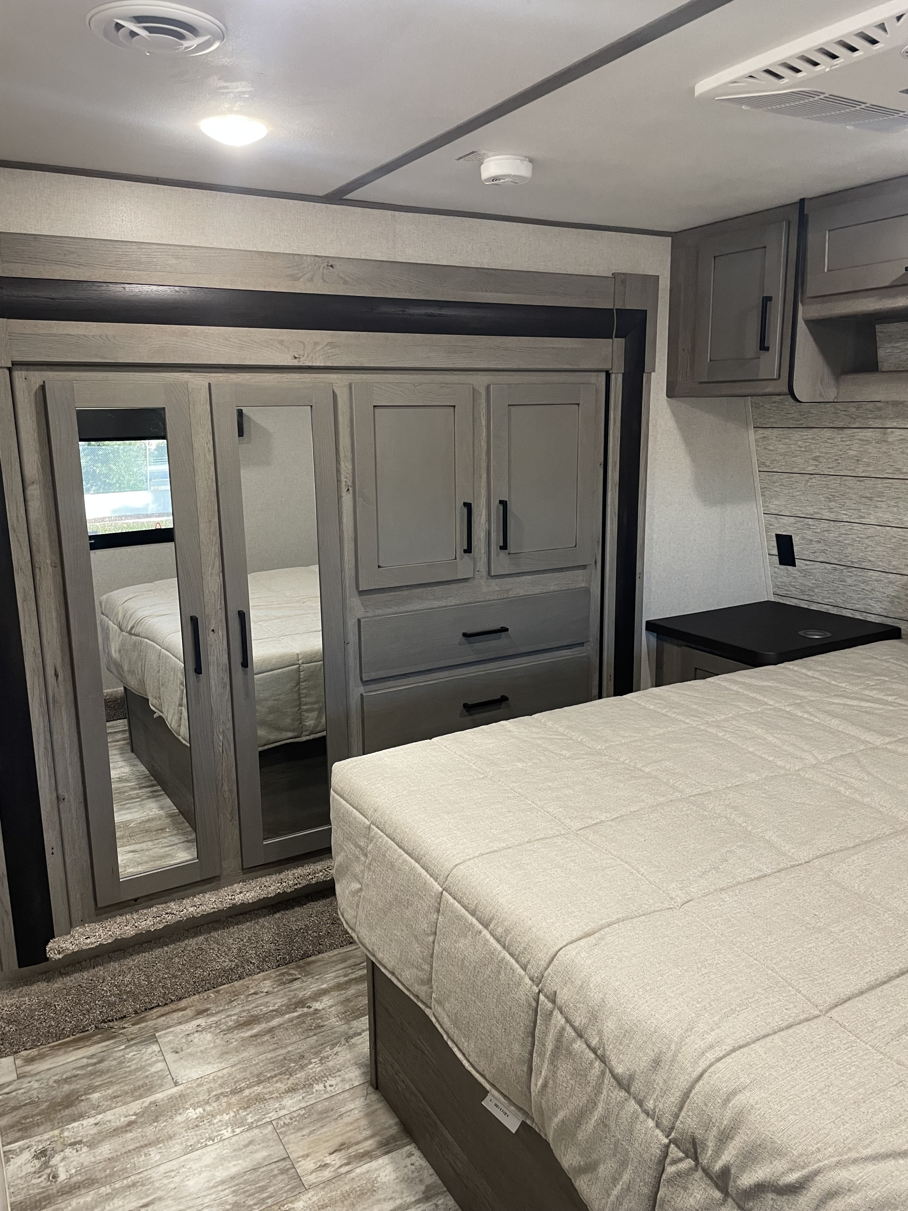 Modern RV rental bedroom with mirrored wardrobe, built-in storage, and a comfy bed. Ideal for your next trip.. Keystone Carbon 2021