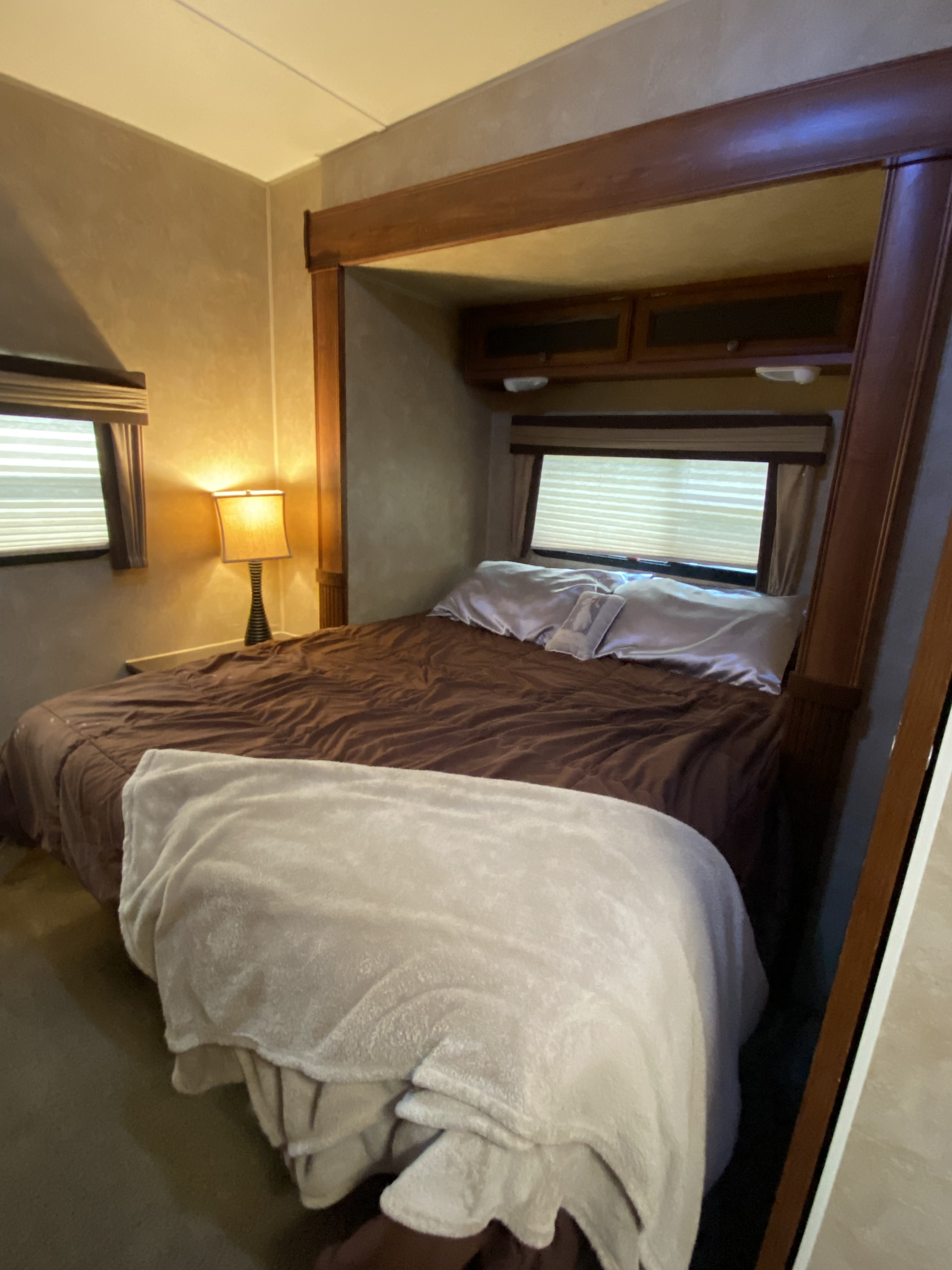 Cozy RV rental bedroom featuring a comfy bed, bedside lamp, and overhead storage, ideal for travels.. Jayco Eagle Super Lite 2012
