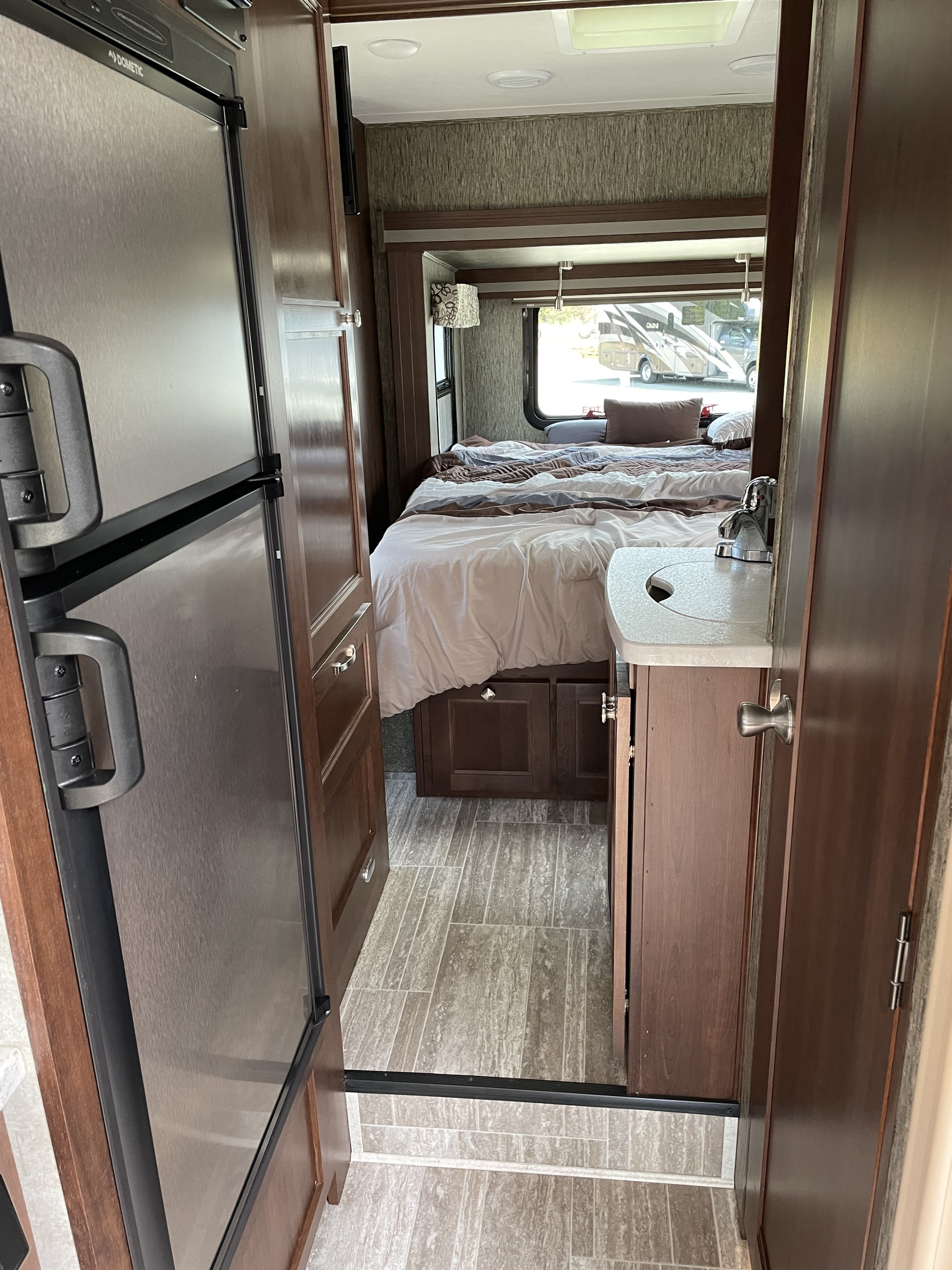 Inside an RV rental, showcasing the kitchen's Dometic fridge, a cozy bedroom, and a compact vanity, ideal for travel.. Forester MBS 2019