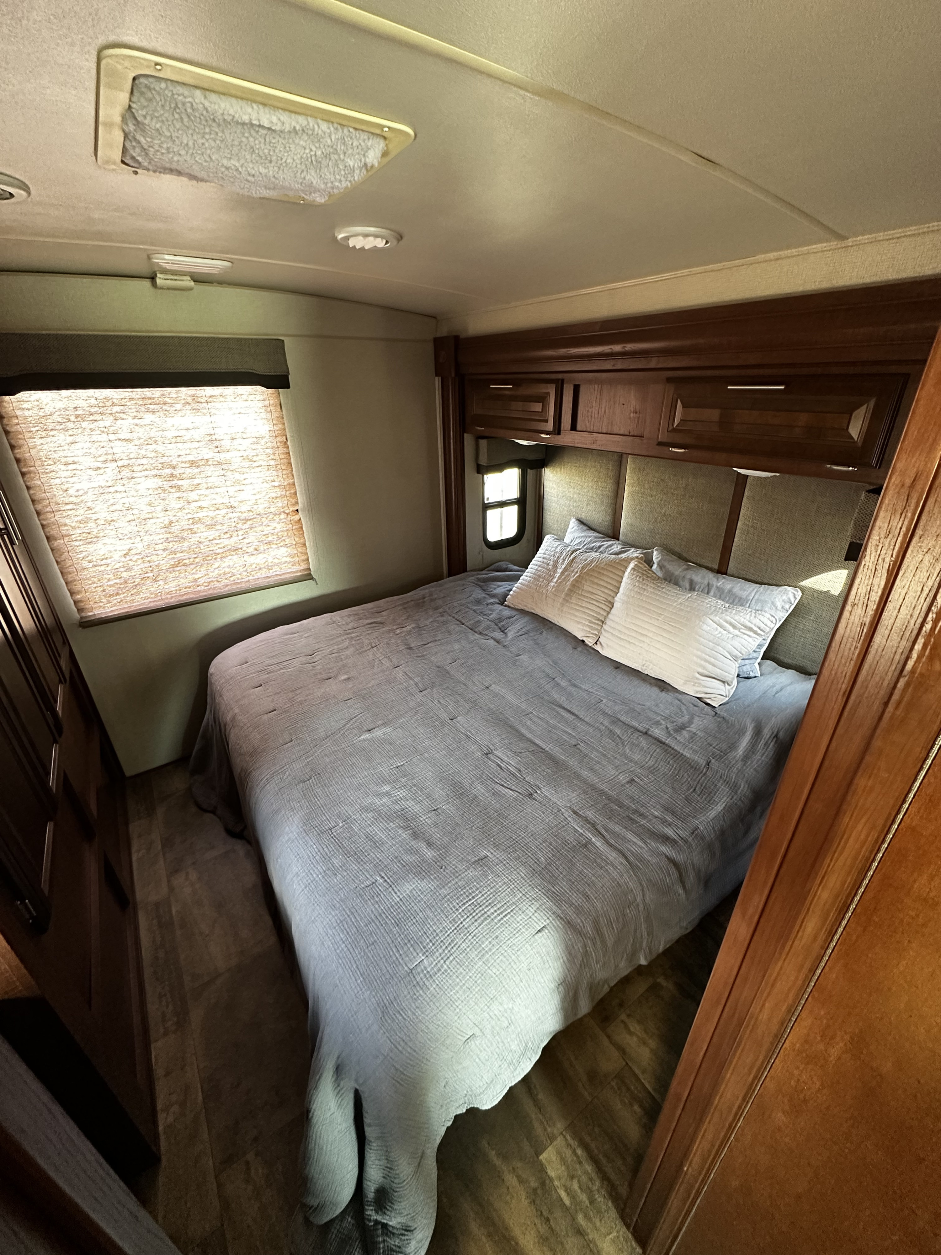 Comfortable RV rental bedroom with a spacious bed, window, and wood cabinetry. Ideal for travel trailer lodging.. Georgetown GT3 2017