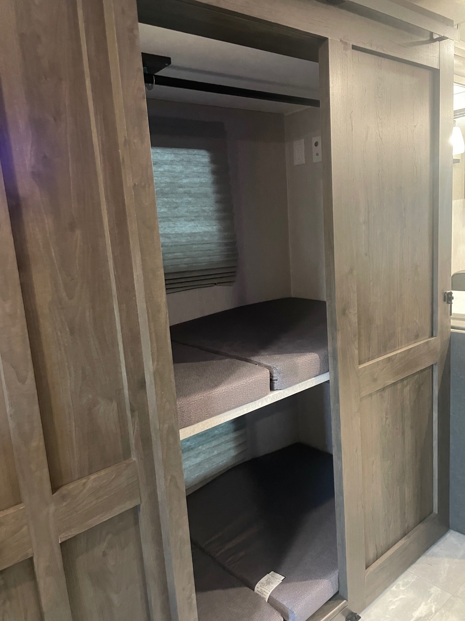 RV rental's bunk beds: two cozy bunks visible in a compact sleeping nook, partially hidden by wooden sliding doors.. Coachmen MIRADA 35ESF 2026