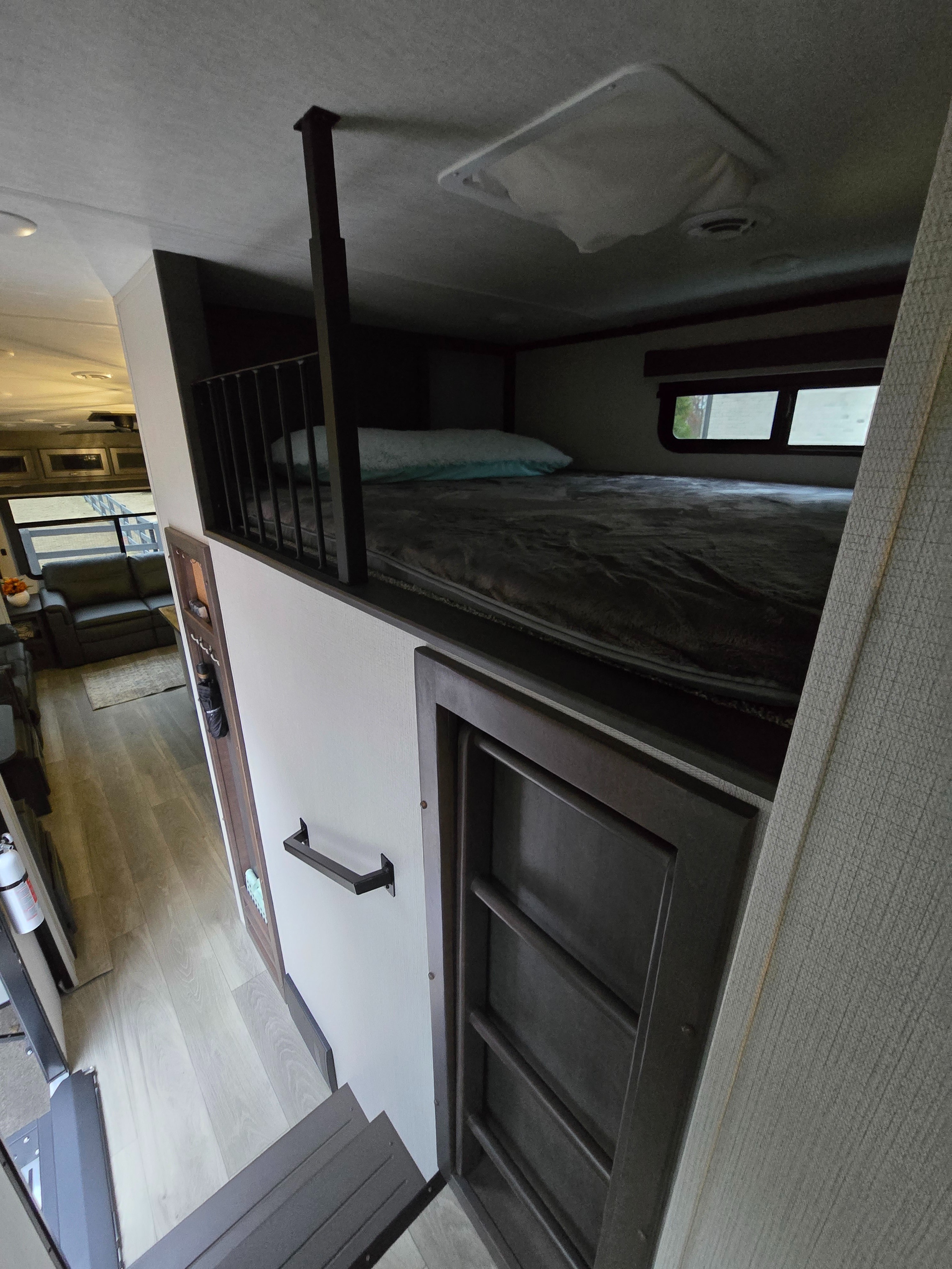 View inside an RV rental, showing a cozy loft sleeping area above steps leading to the main living space.. Keystone RV Cougar 2024