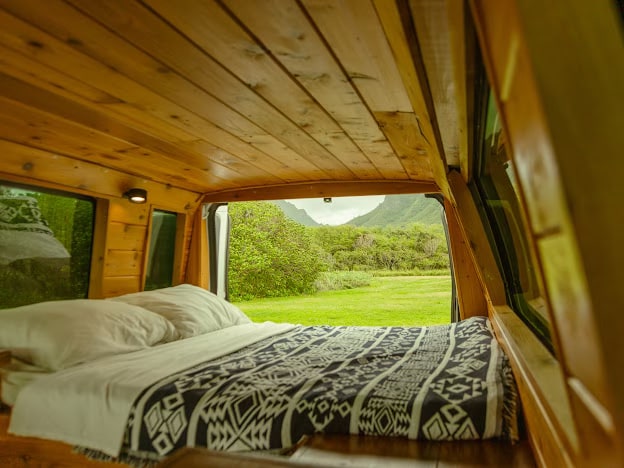 Experience van life! This RV rental features a cozy wood interior with a bed & panoramic views of green fields & mountains.. Ford Ford E350 2012