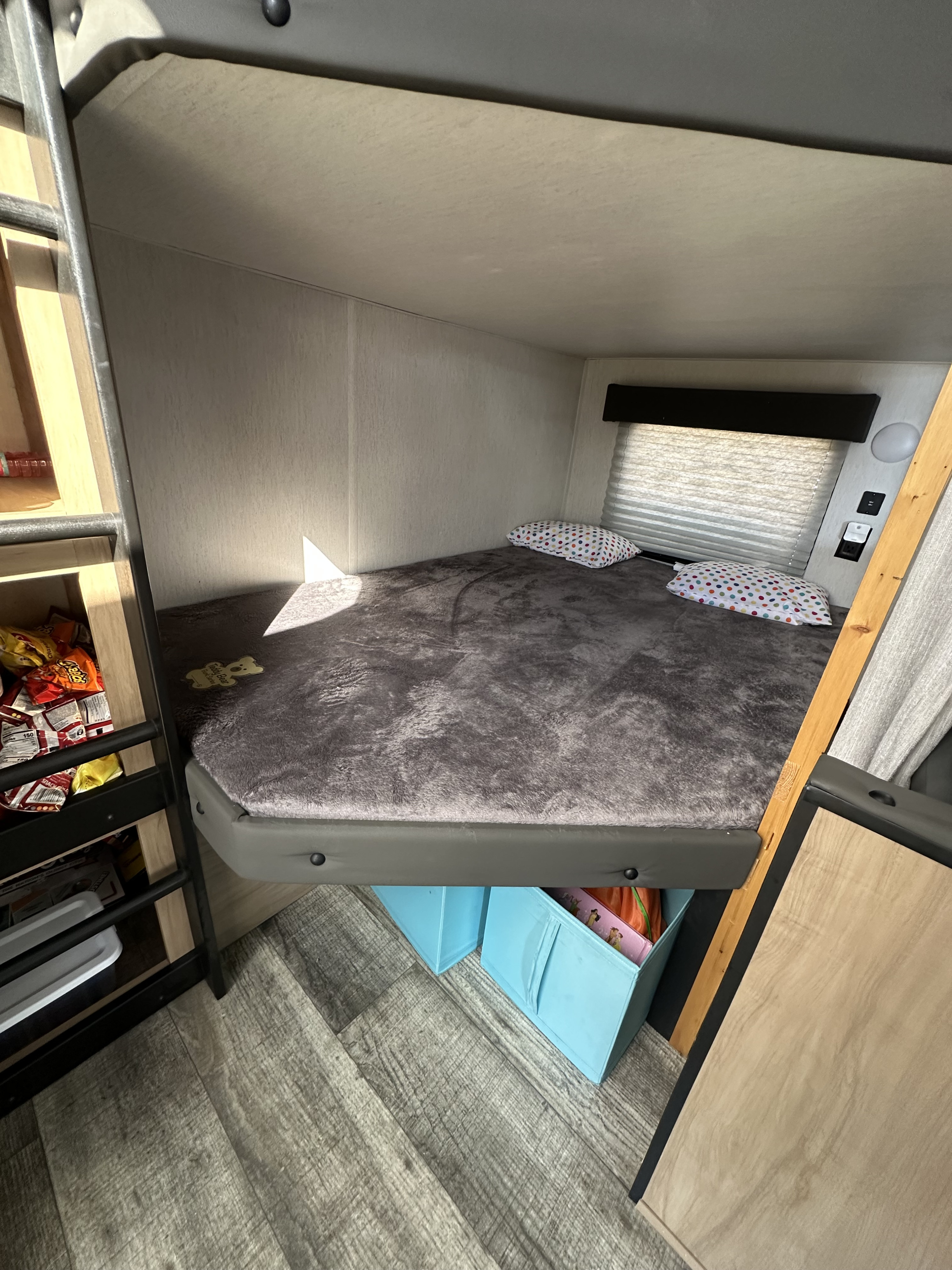 RV rental bunk bedroom: cozy bed with colorful pillows, window, and smart storage.. Forest River Cherokee 2023