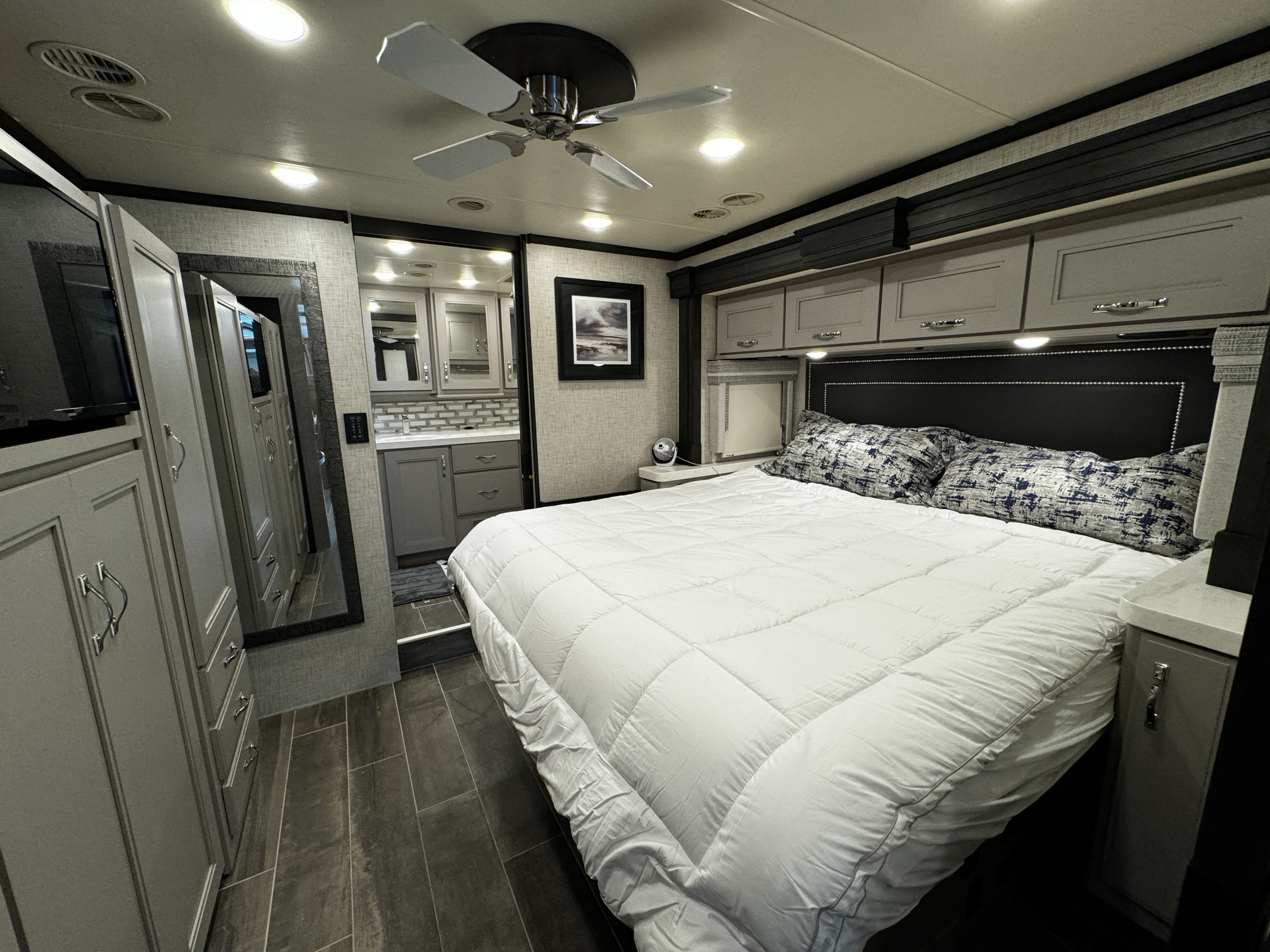Spacious and modern RV rental bedroom featuring a comfortable bed, ample storage, and an en-suite bathroom view.. Thor Tuscany 2023