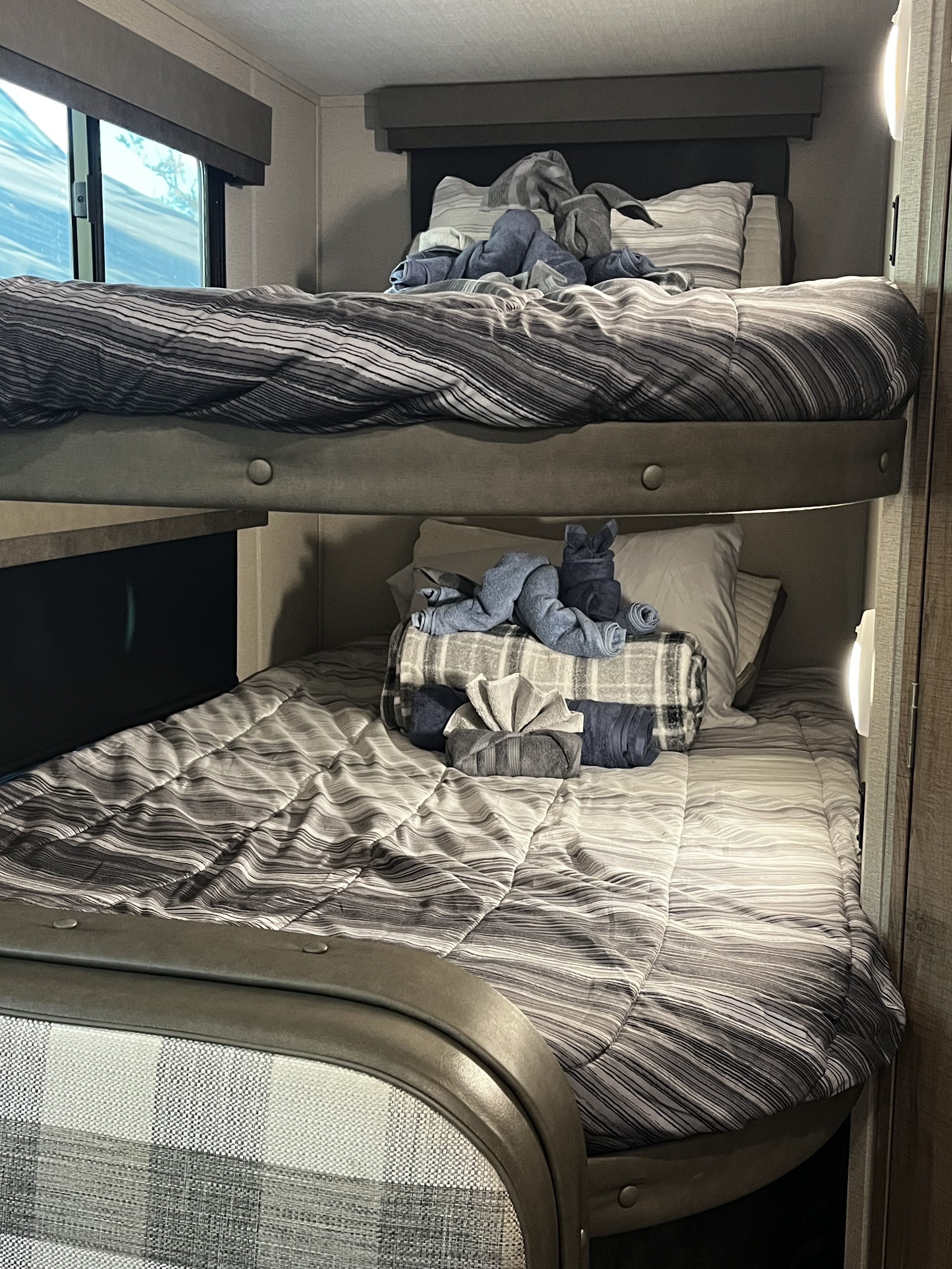 RV rental bunk beds: two cozy bunks with striped bedding and adorable towel animals. A perfect space for family travel.. Grand Design Imagine XLS 2021