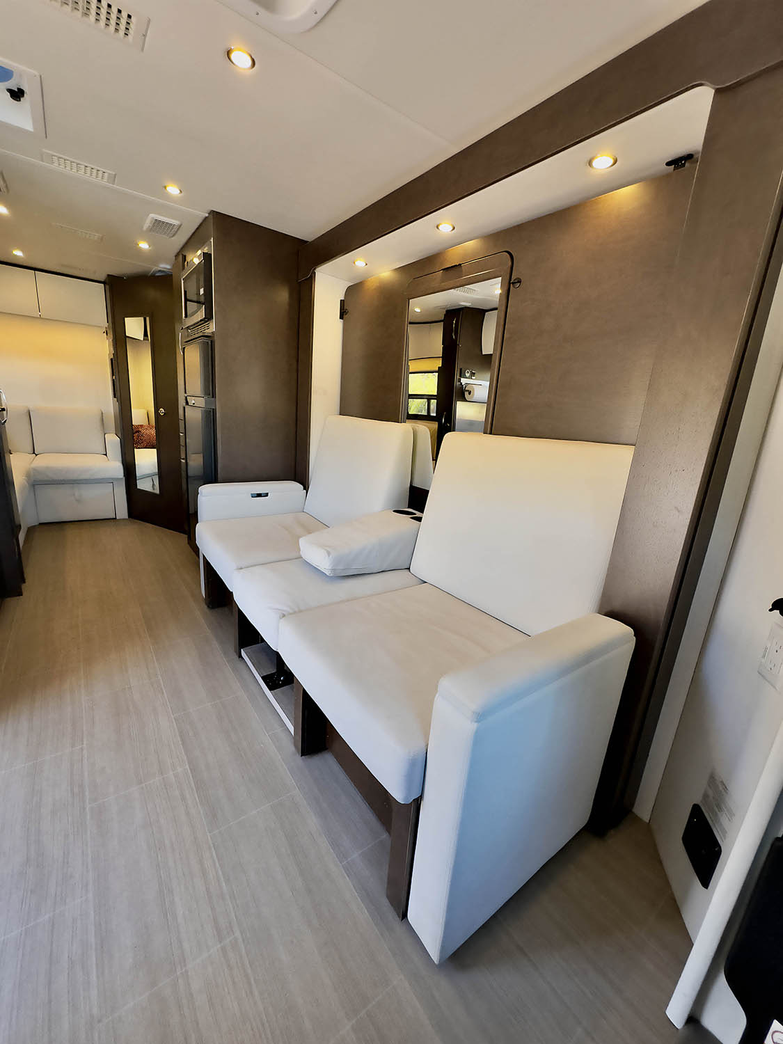 Experience a modern RV rental interior featuring plush cream recliners, ample lighting, and a well-equipped layout.. Leisure Travel Vans Unity 2022