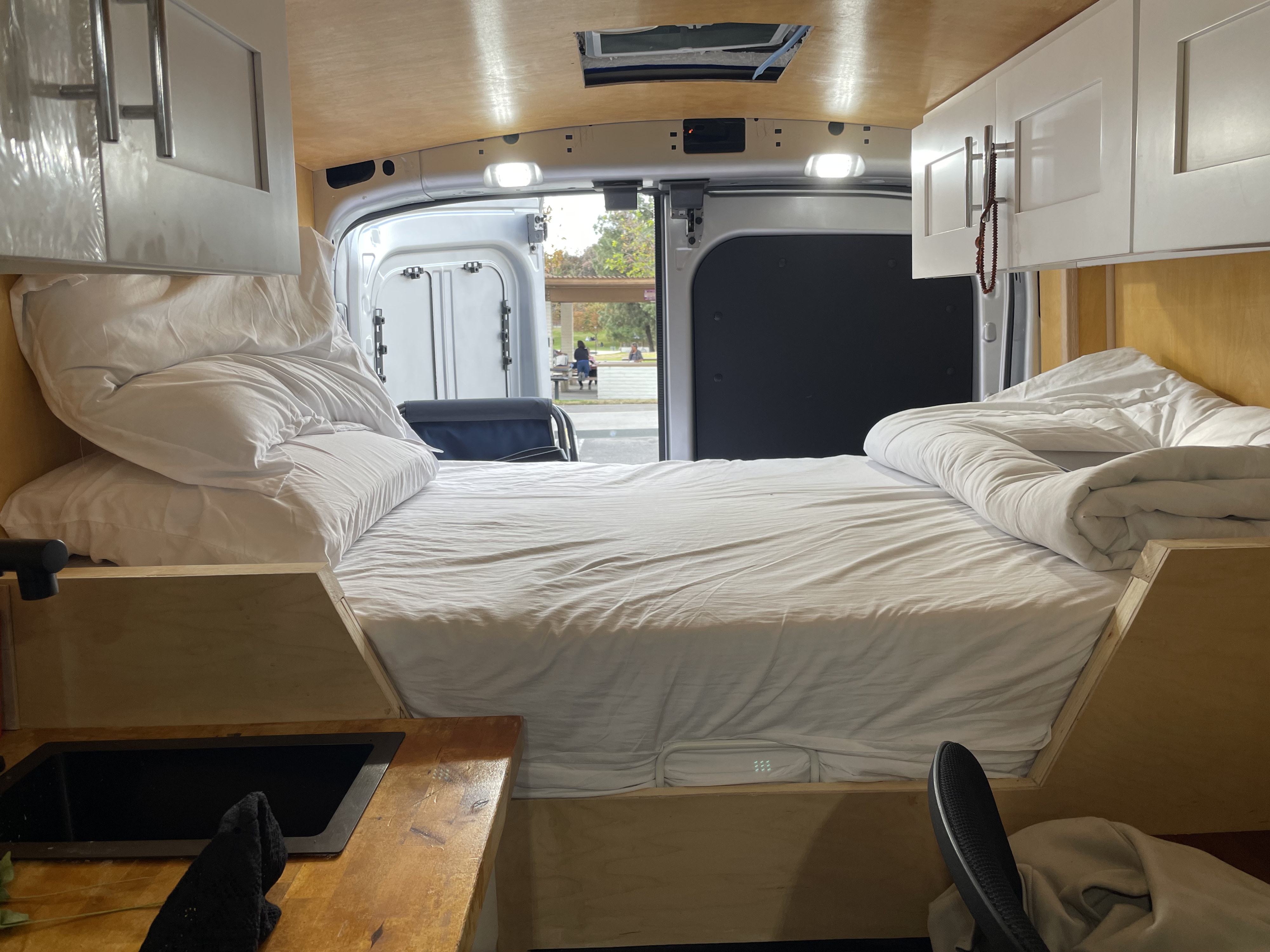 RV rental: Enjoy van life in this cozy camper with a comfy bed, kitchenette, and park views out the back.. Ford Transit 2023