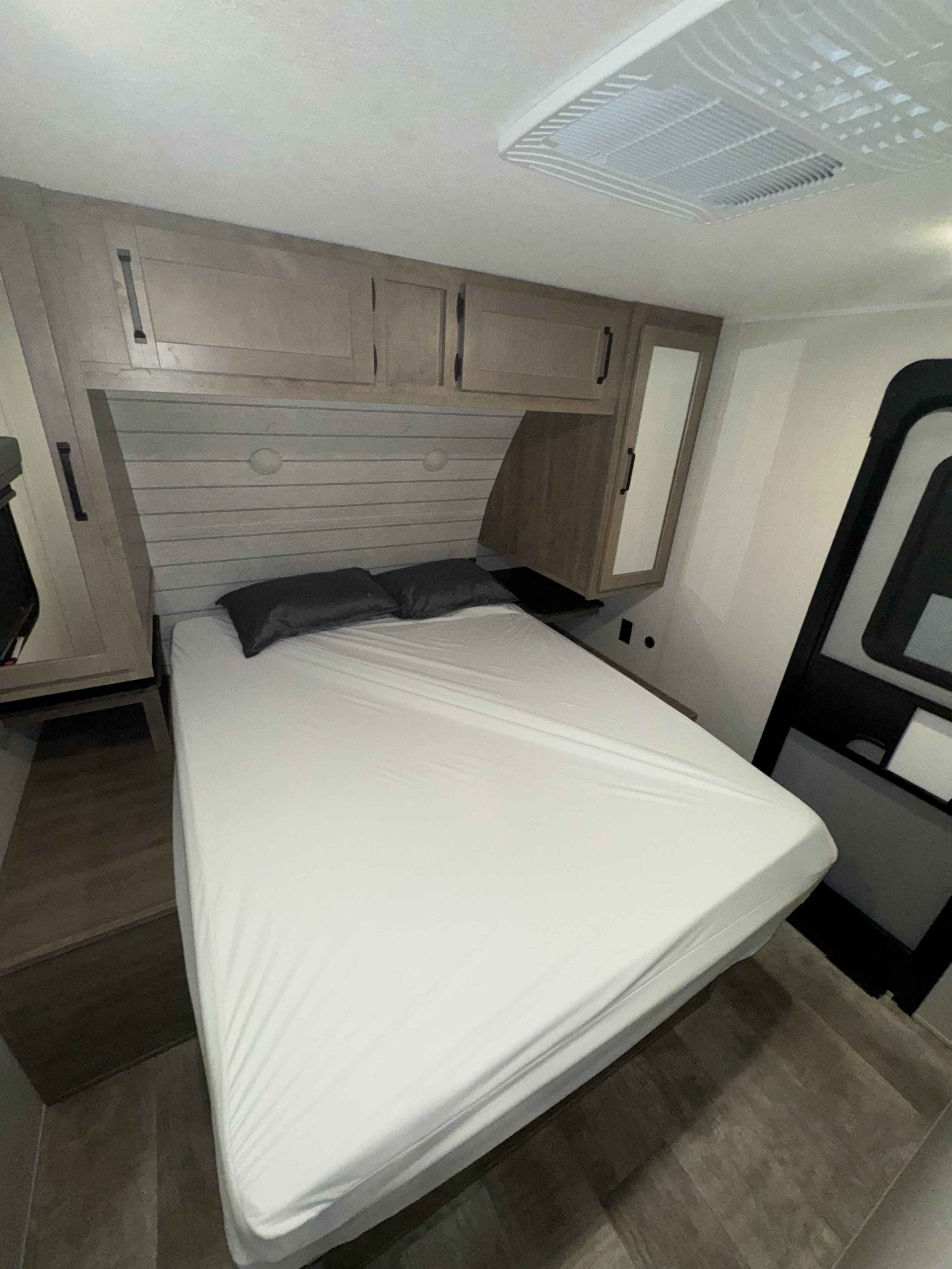 RV rental bedroom showcasing a white bed, light wood cabinets, AC unit, and mirrored wardrobe, perfect for comfortable travel.. 4x4tpug23rp102883 31qbbh 2024