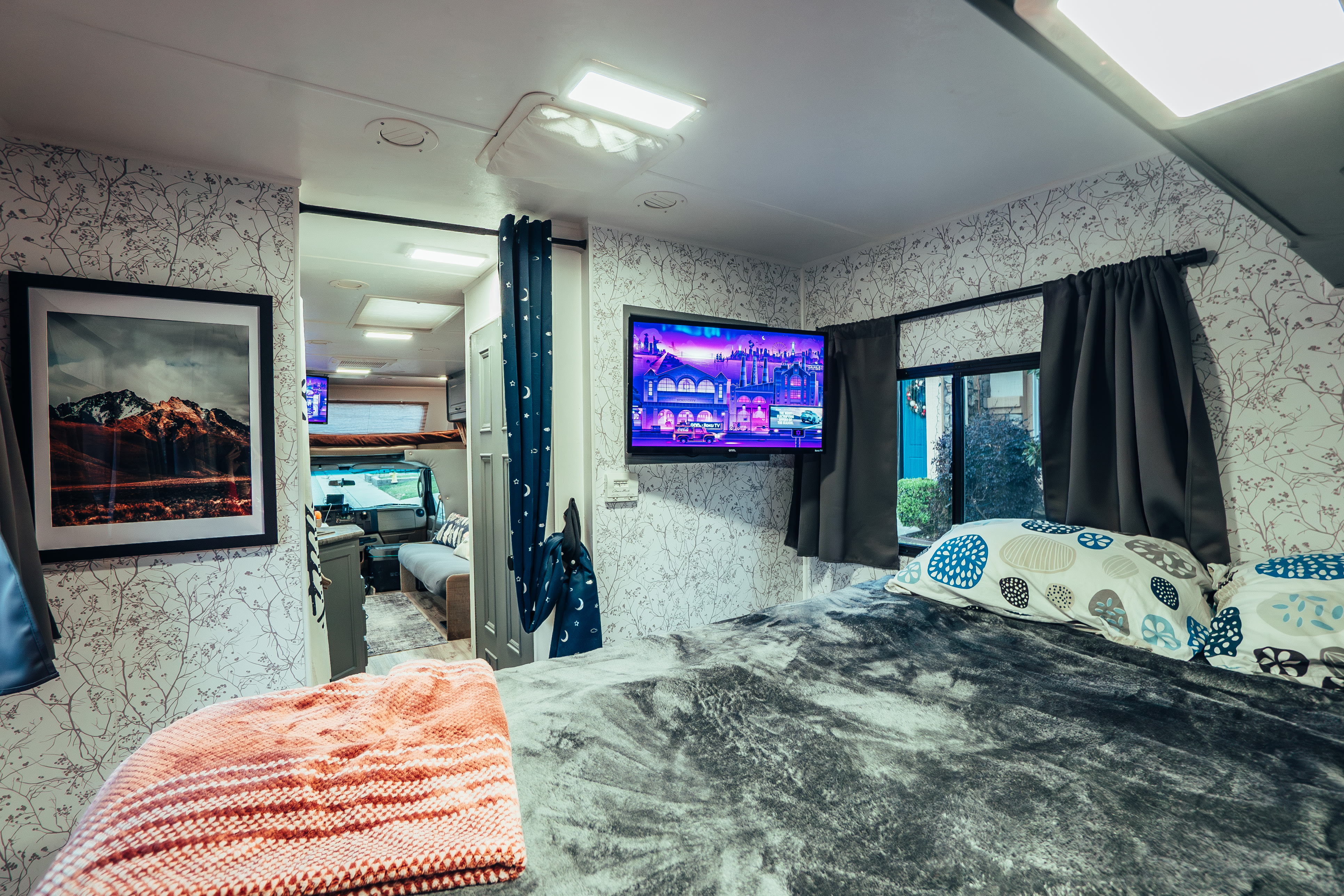 Cozy RV rental bedroom featuring a mounted TV, patterned walls, and a plush bed. A perfect mobile retreat.. Four Winds Four Winds Motorhome 2011