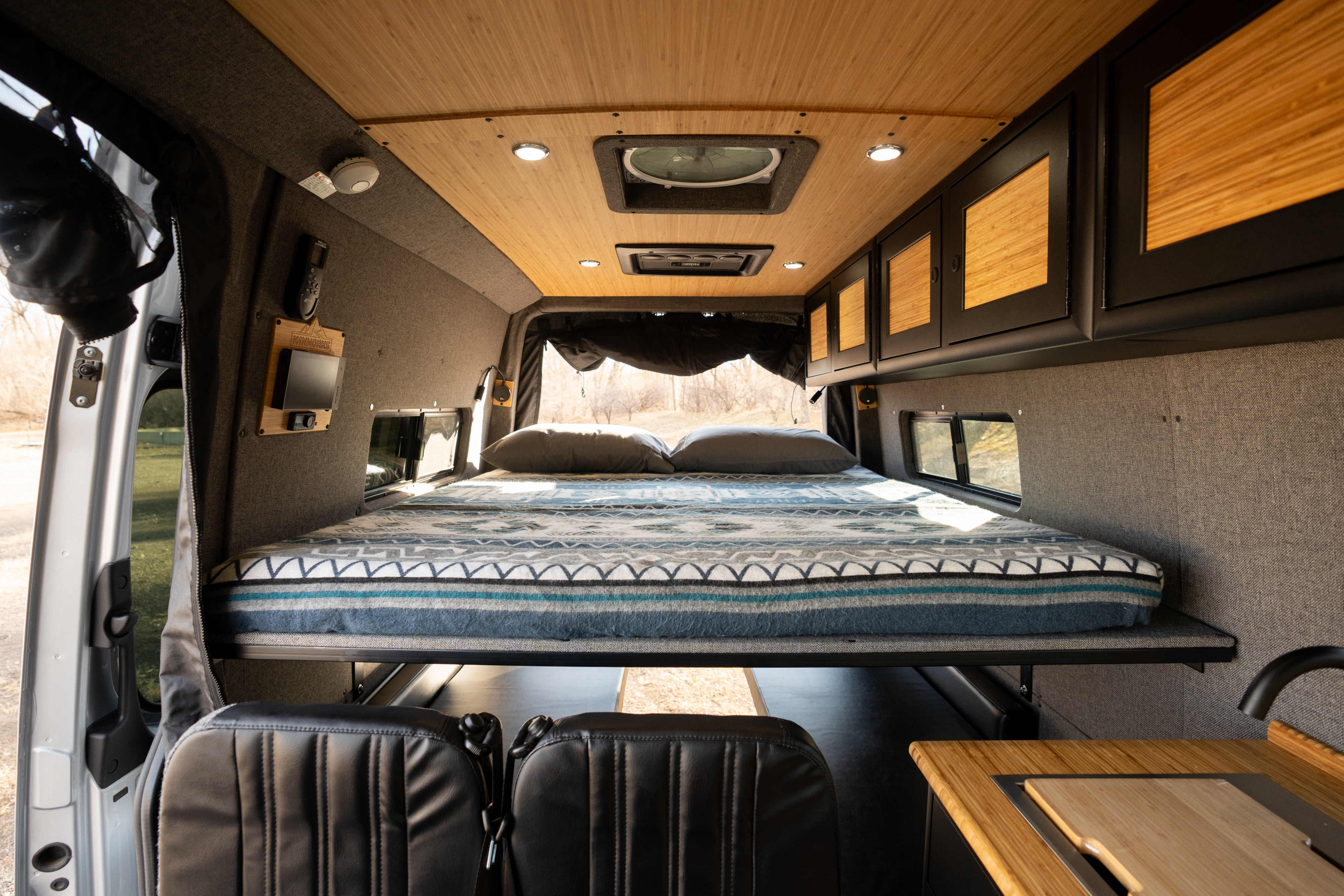 Explore van life in this cozy rv rental camper. Inside: comfy bed, bamboo ceiling, cabinetry, and compact kitchen.. Mercedes-Benz Sprinter 2024
