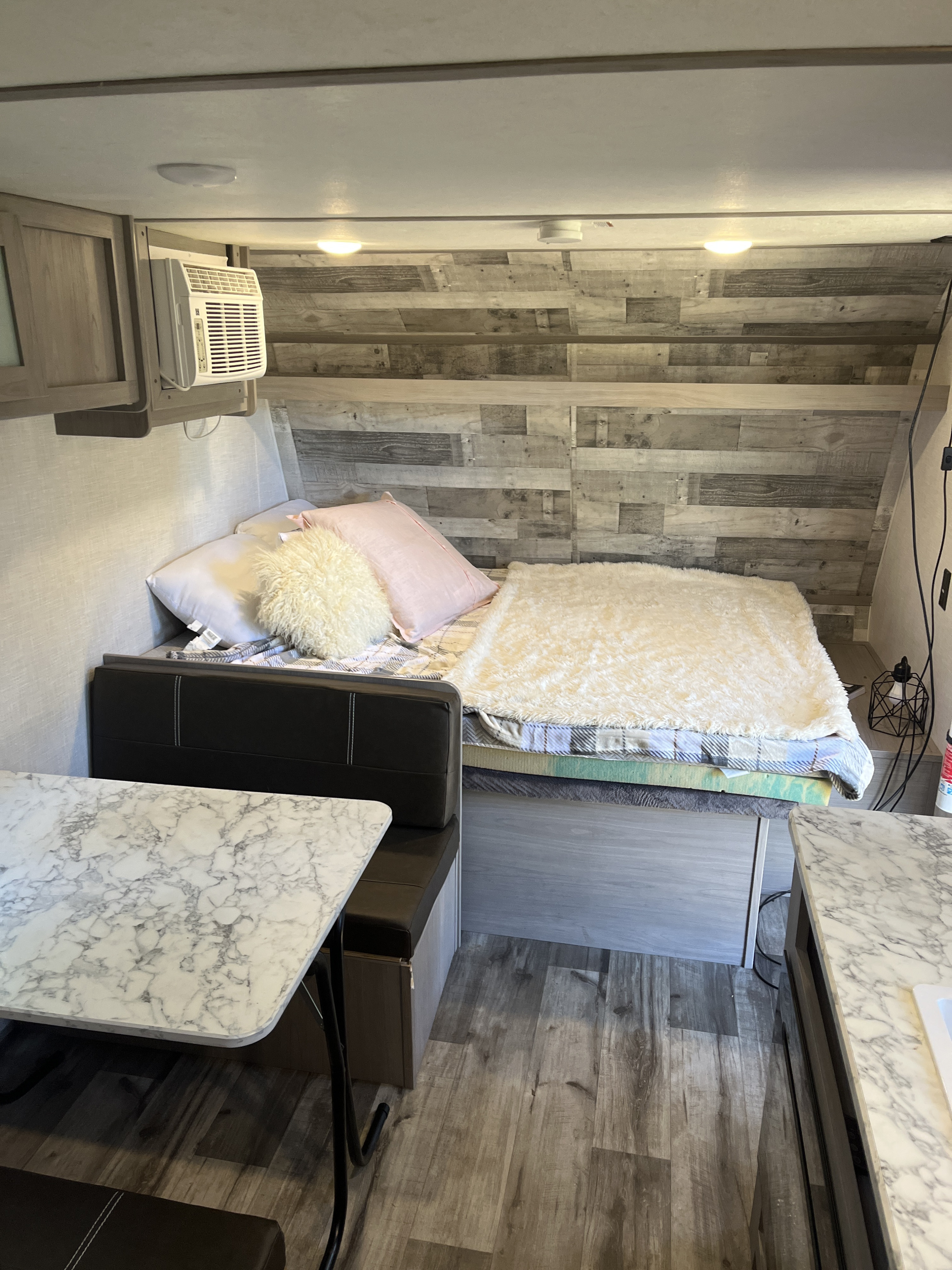 RV rental interior: cozy bed with blankets, built-in dinette, and AC unit create a comfortable travel space.. Coachmen 17b 2023