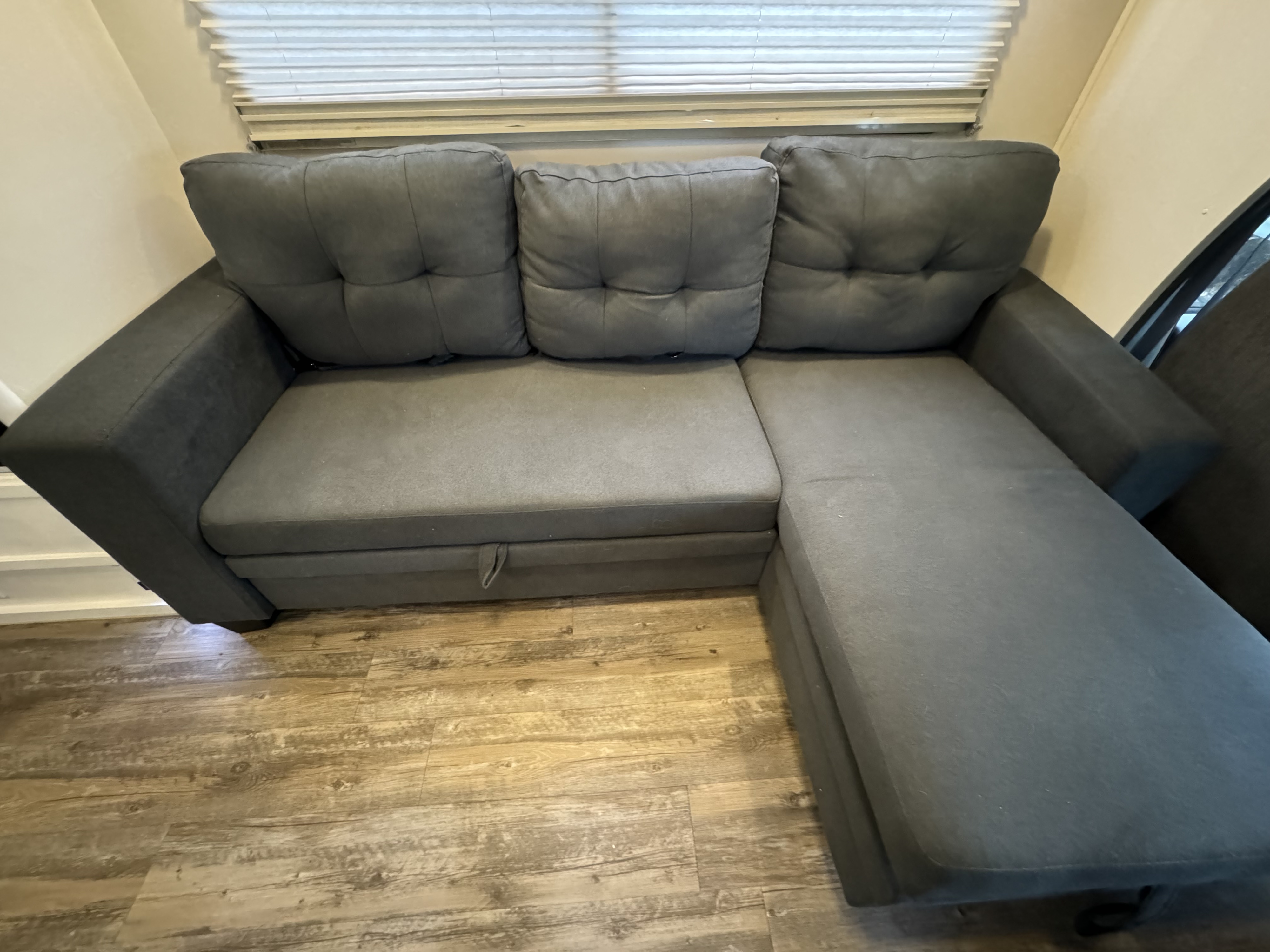 Comfortable gray sectional sofa with pull-out bed, ideal for an RV rental interior.. Winnebago Minnie 2002