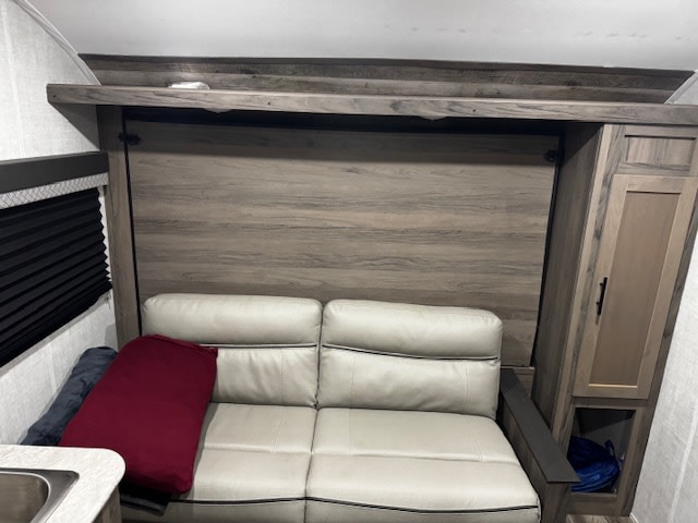 RV rental: Modern RV interior with a light-colored sofa and integrated wood-look murphy bed unit.. Gulf Stream Kinsport Super Lite 2022