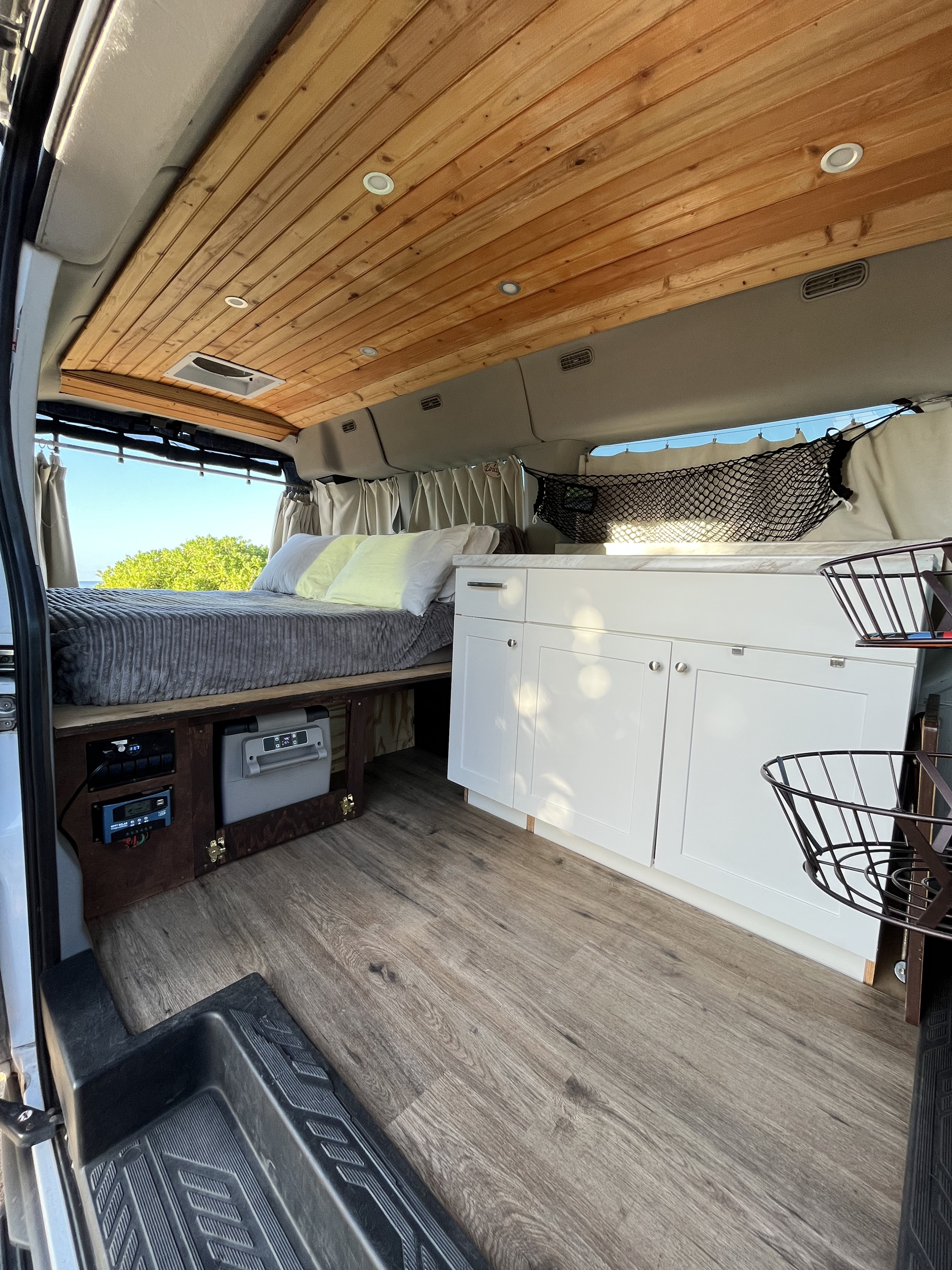 Modern RV rental interior featuring a comfy bed, kitchen, wood ceiling, and scenic window views.. Ford Transit 2015