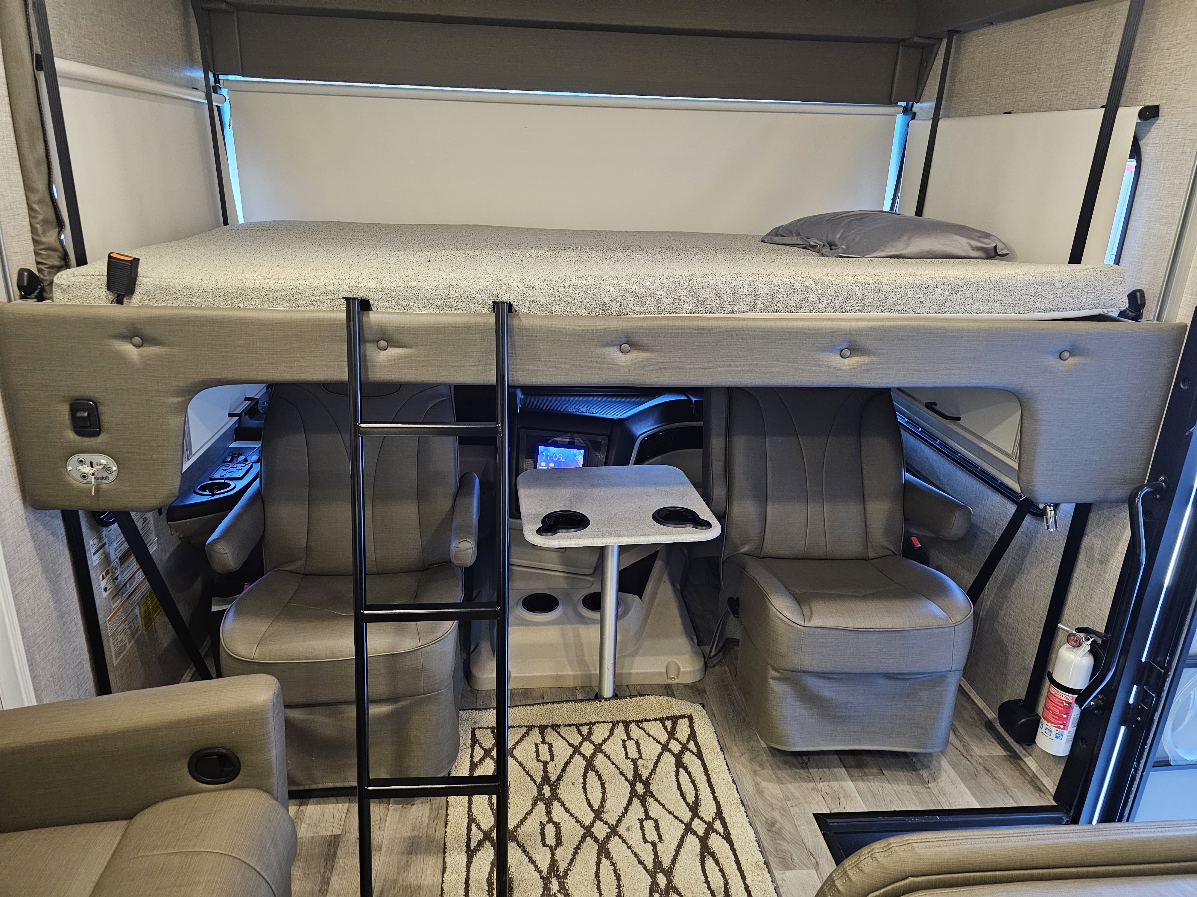 Discover an RV rental interior: a cab-over bunk with ladder, swiveling captain's chairs, and a removable table.. Jayco Alante 2022