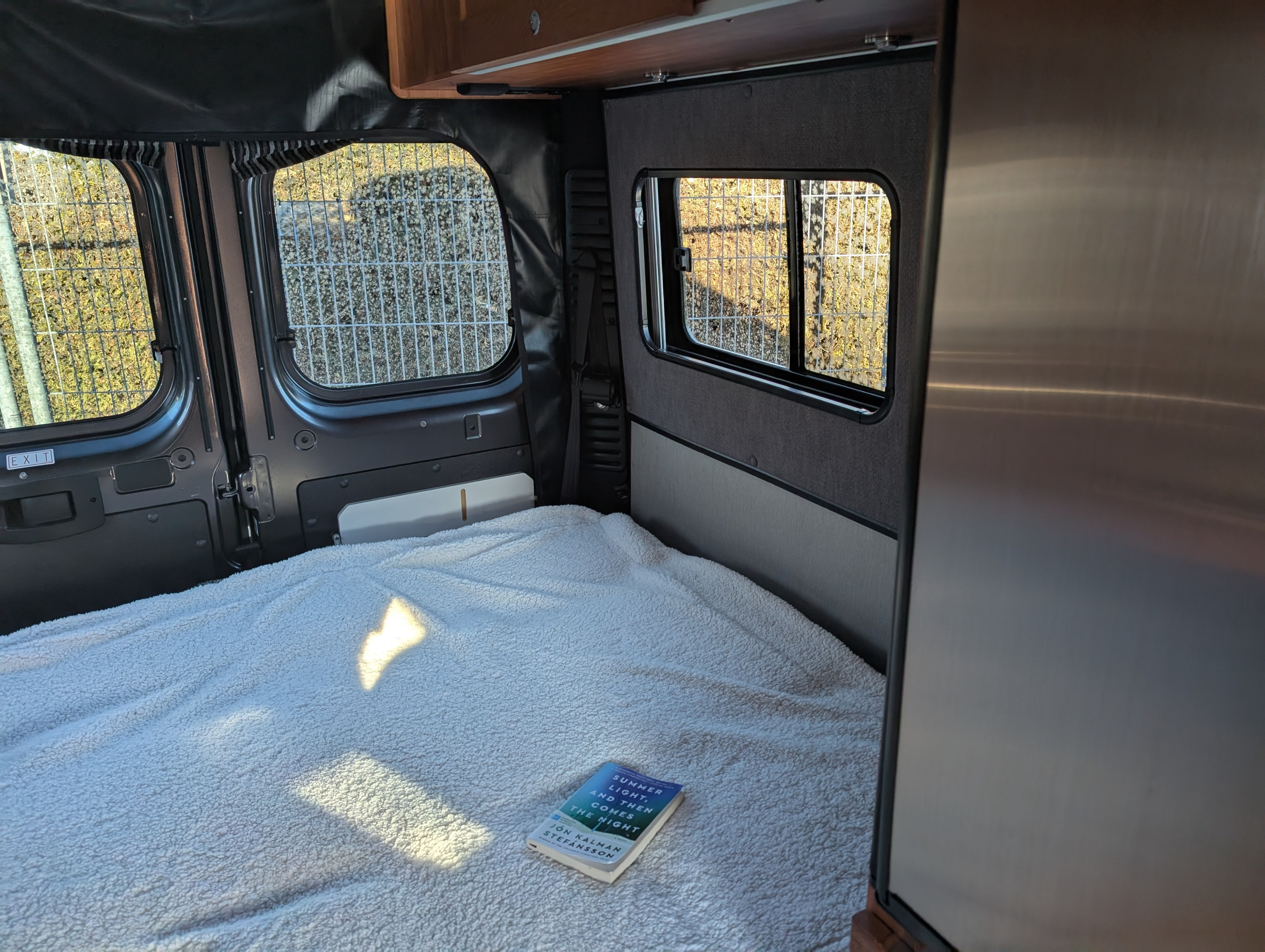 RV rental interior: A cozy bed with a book, bathed in sunlight. Perfect for your next adventure.. Roadtrek Roadtrek Class B 2019