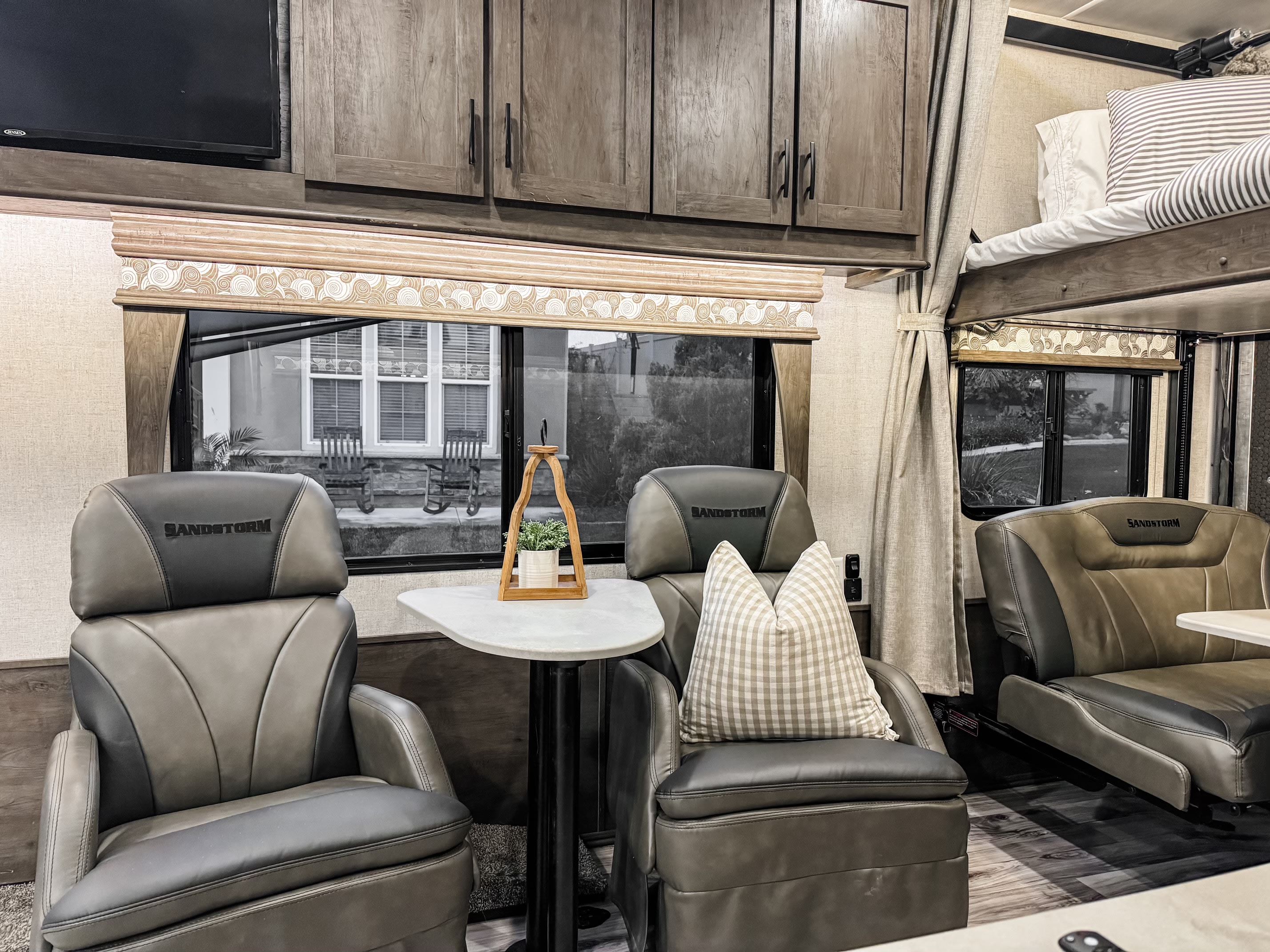 Comfortable RV rental interior with Sandstorm seating, a bunk bed, overhead cabinets, and large windows.. Forest River Sandstorm 2021