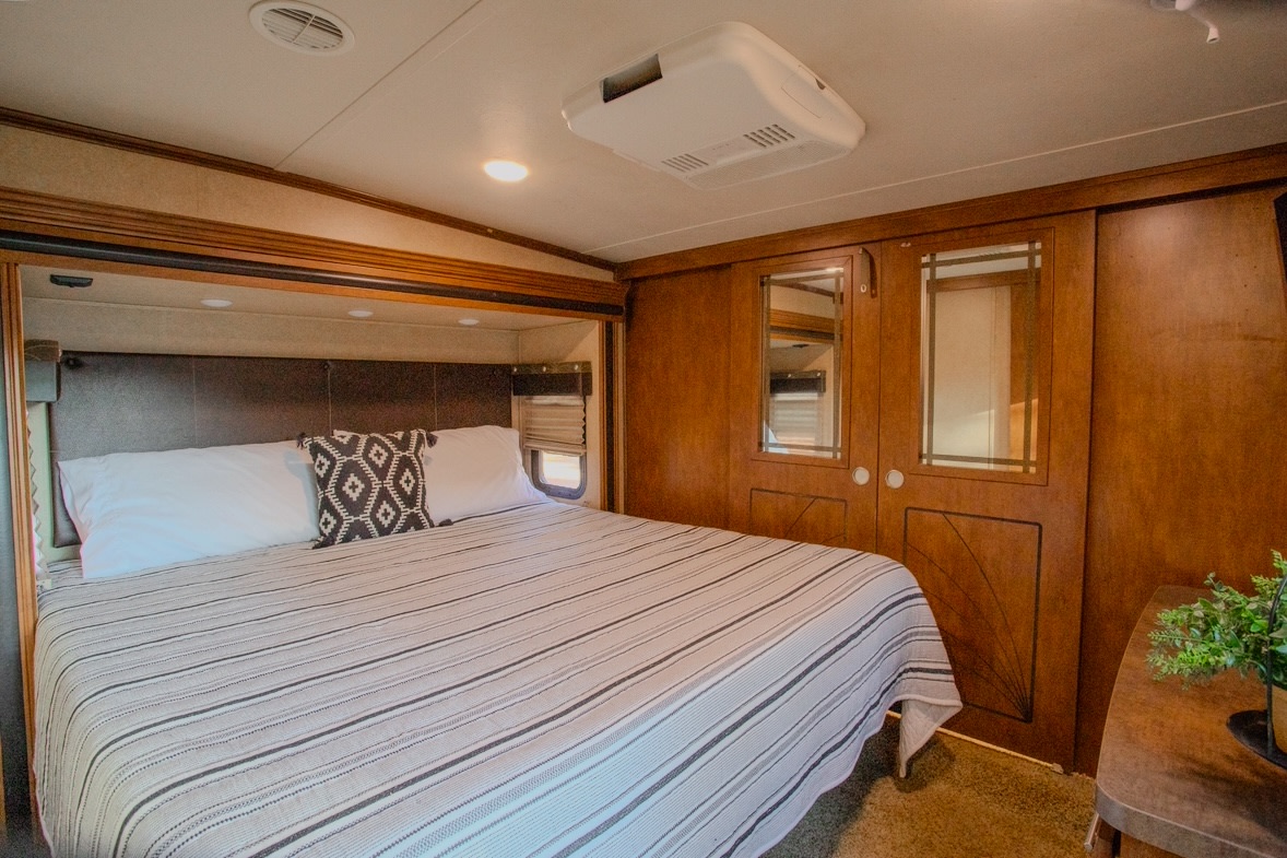 Step inside this inviting RV rental bedroom with a comfy bed, integrated storage, and AC unit, perfect for travel comfort.. Forest River XLR Thunderbolt Toy Hauler 2014
