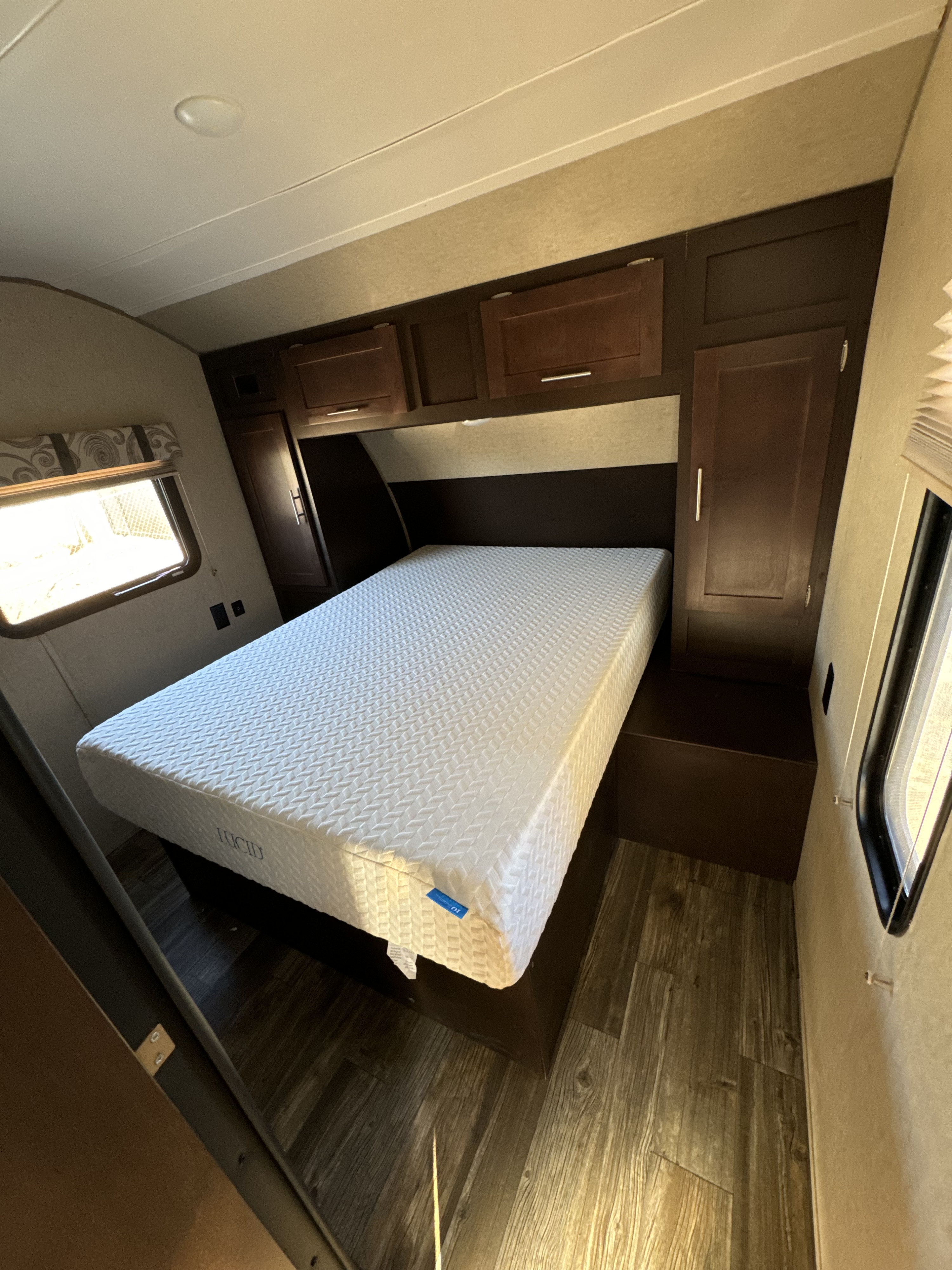 Clean RV rental bedroom with a white Lucid mattress, built-in storage, and a window. Ideal for road trip comfort.. Forest River Cherokee Grey Wolf 2016