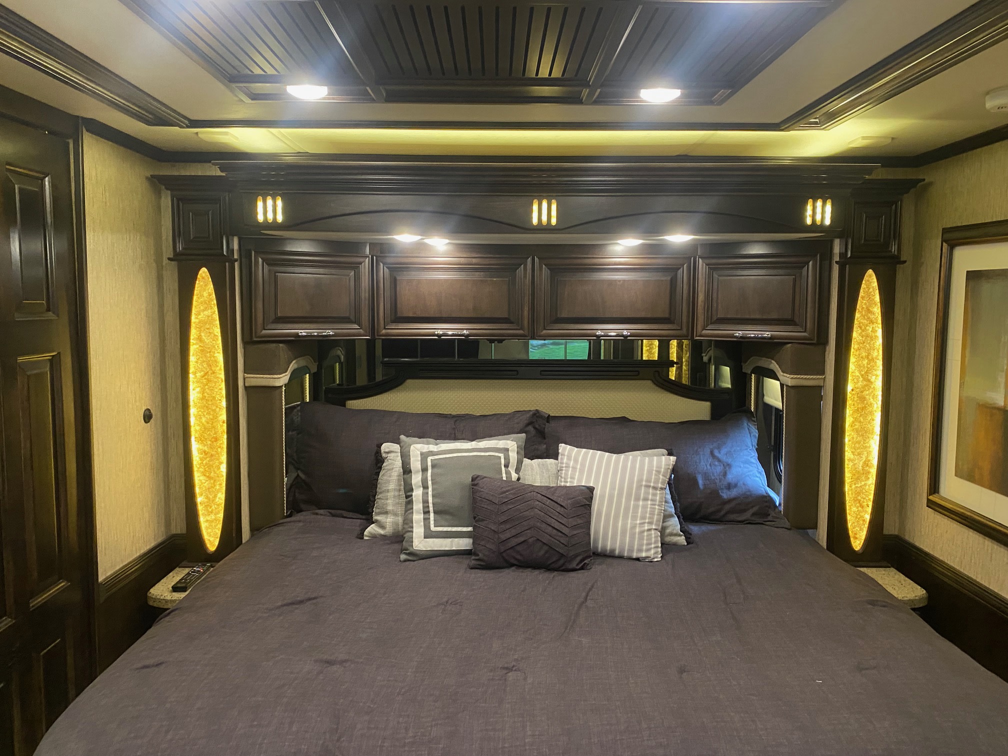 Luxurious RV rental bedroom featuring dark wood built-ins, abundant ambient lighting, and a comfortable bed.. Mountain Aire Mountain Aire Motorhome 2016