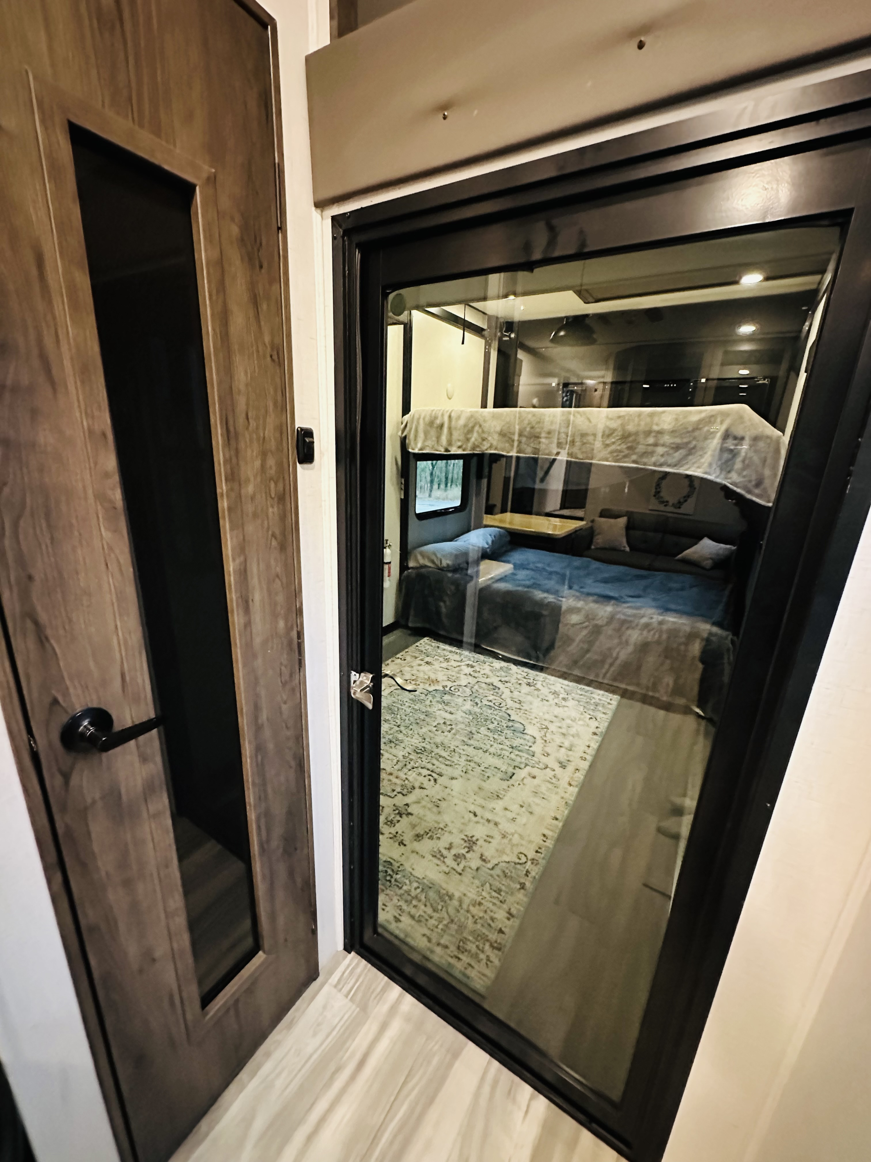 RV rental interior showcasing a bunk room with beds, a sofa, and rug, visible through a glass door.. Alliance Valor 40v13 2022