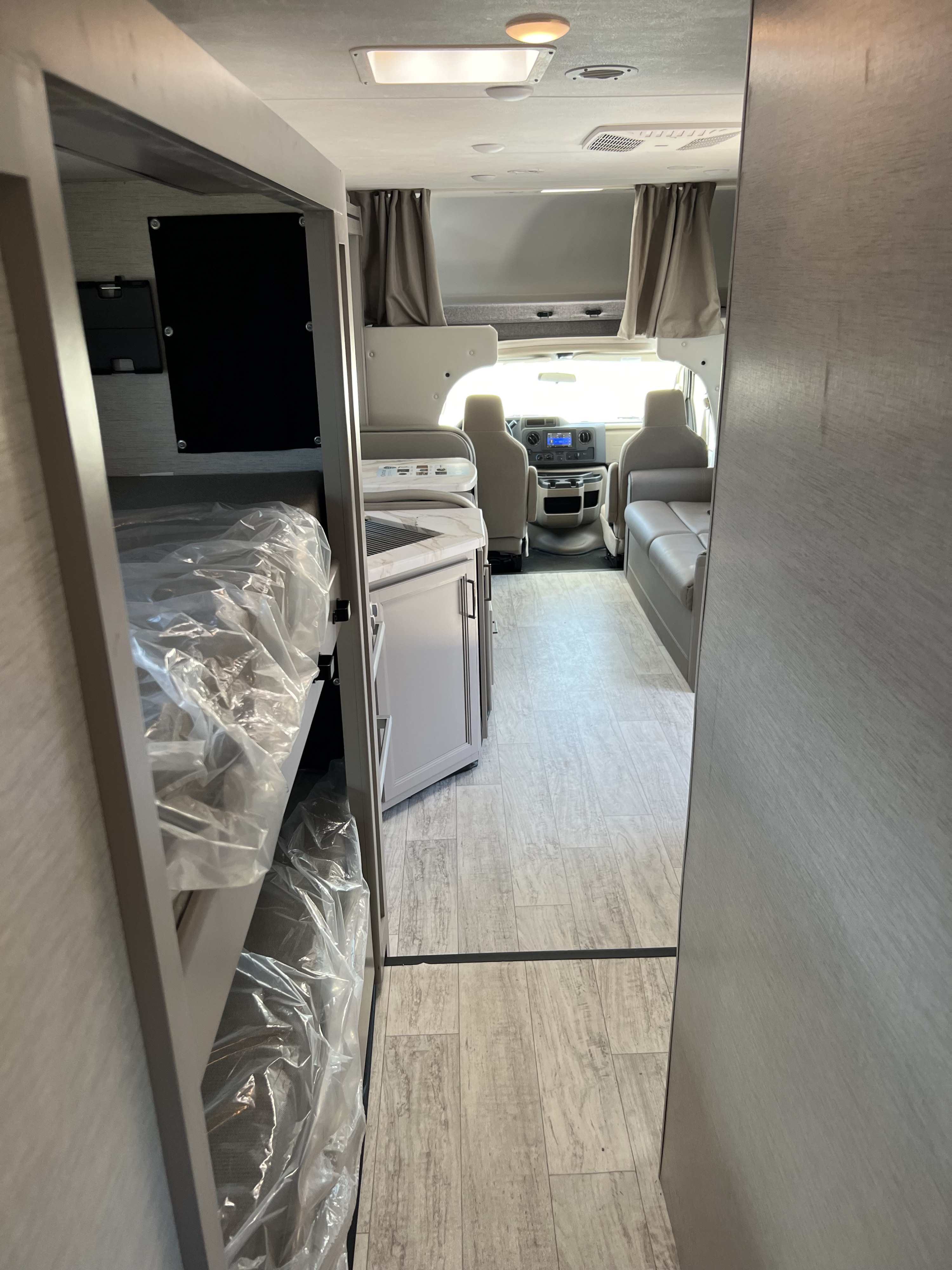Inside an RV rental: View from the bunk beds to the front cockpit, featuring a compact kitchen. Your next camper awaits!. Thor Motor Coach Chateau 2024