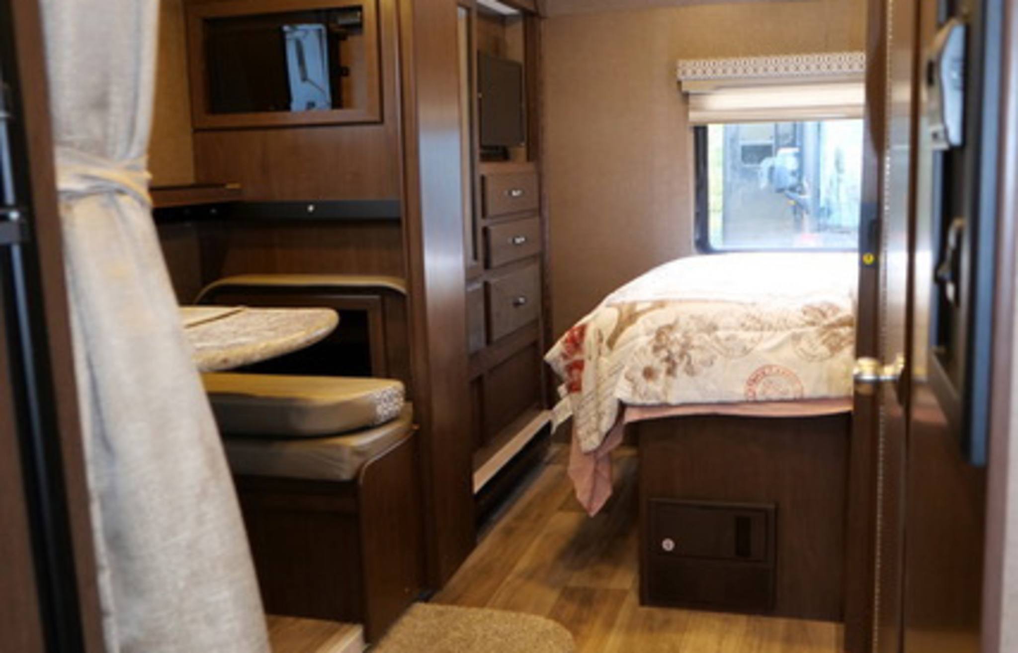 Cozy RV rental interior showcasing a compact dinette, built-in storage, and comfortable bedroom area.. Thor Freedom Elite 2018