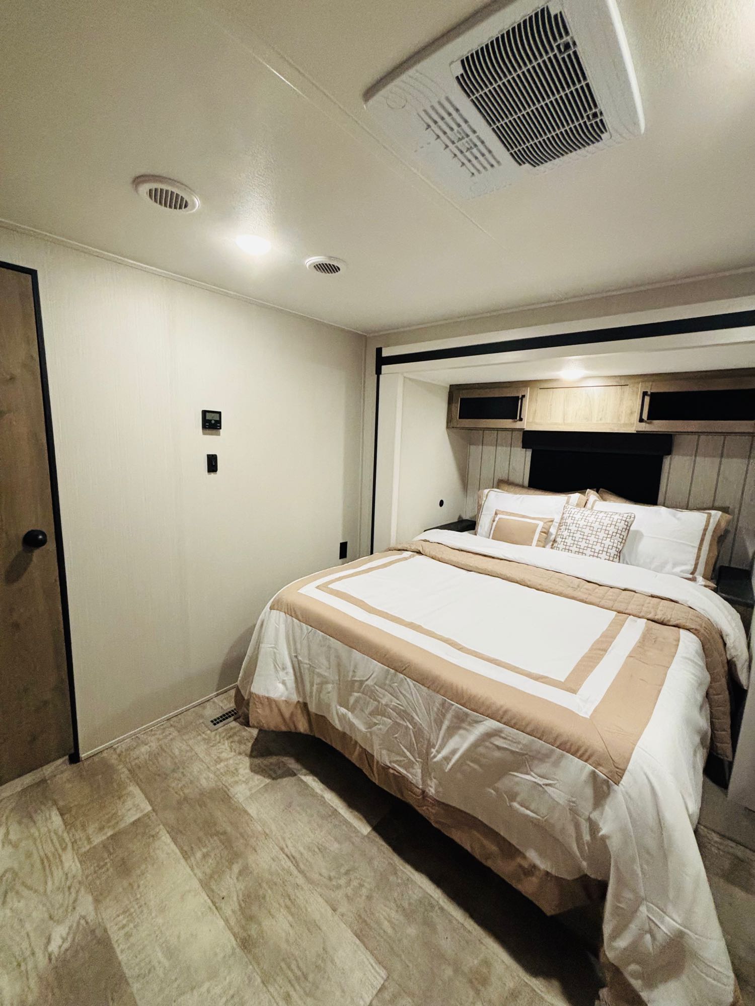 Comfortable RV rental bedroom featuring a neatly made bed, overhead storage, AC, and thermostat for a cozy retreat.. Forest River Palomino Puma 2025