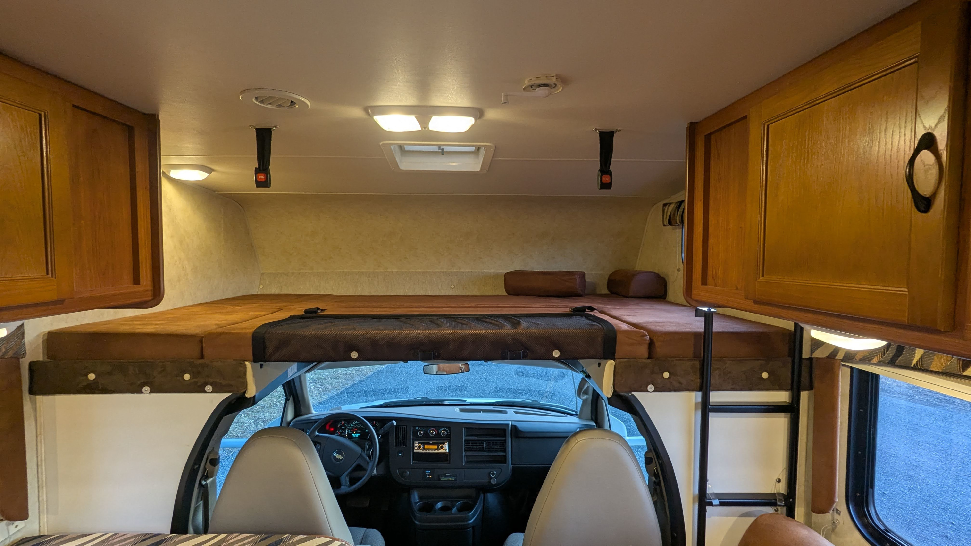 RV rental interior view. Class C motorhome with a large cab-over bunk bed, dashboard, and storage cabinets.. Forest River Coachmen Freelander 2013