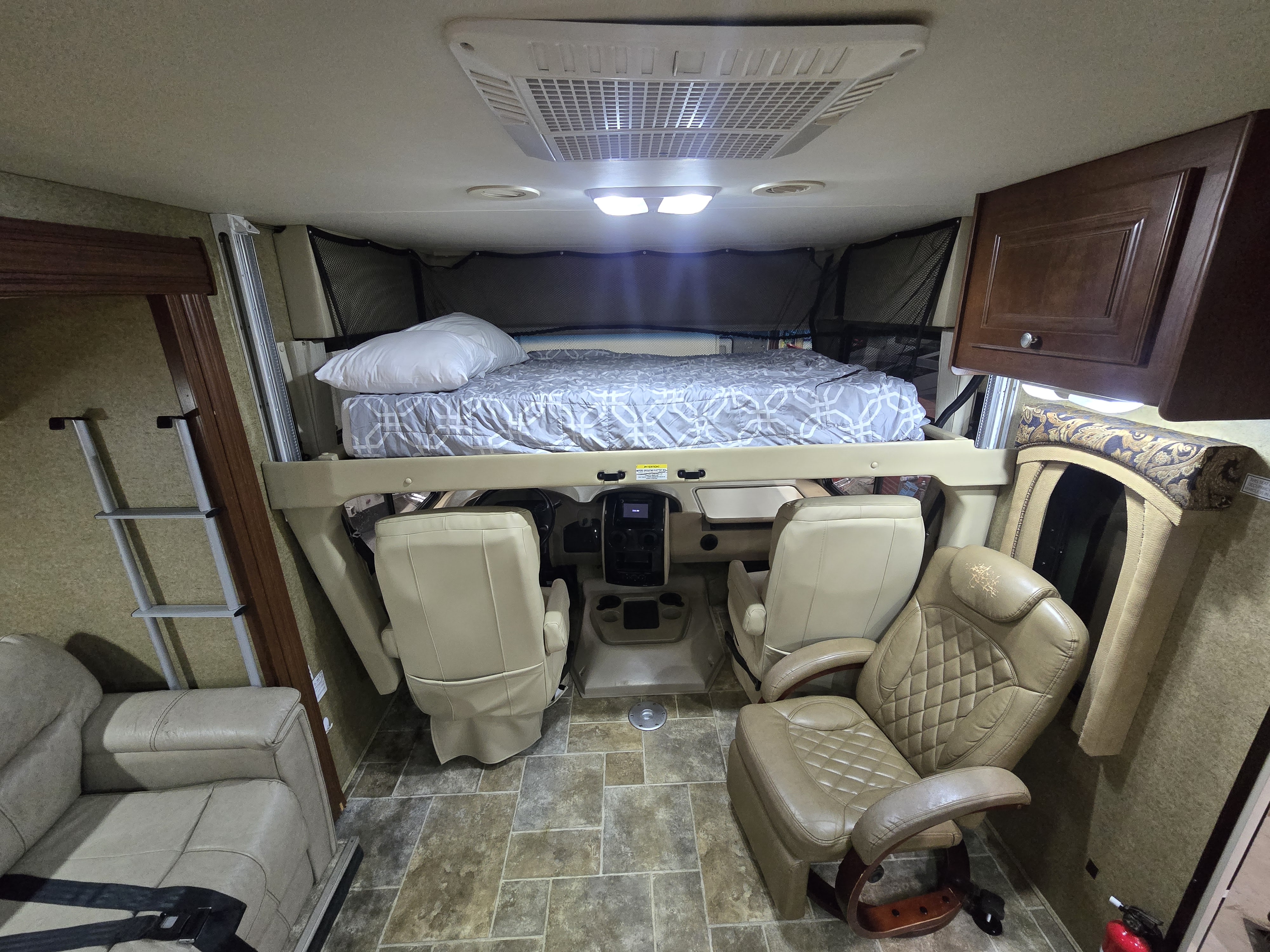 RV rental interior: elevated cab-over bunk, driver's cockpit, and lounge seating for comfortable travel.. Thor Motor Coach Miramar 2014