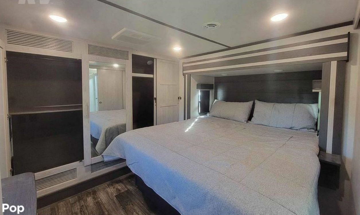 Modern RV rental bedroom featuring a large bed, mirrored closets, and sleek interior for comfortable travel.. Keystone Fuzion 2021