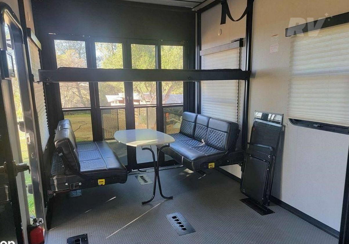 RV rental: Toy hauler's versatile interior with bunk bed, wall-mounted sofas, and dining area, ideal for trips.. Keystone Fuzion 2021