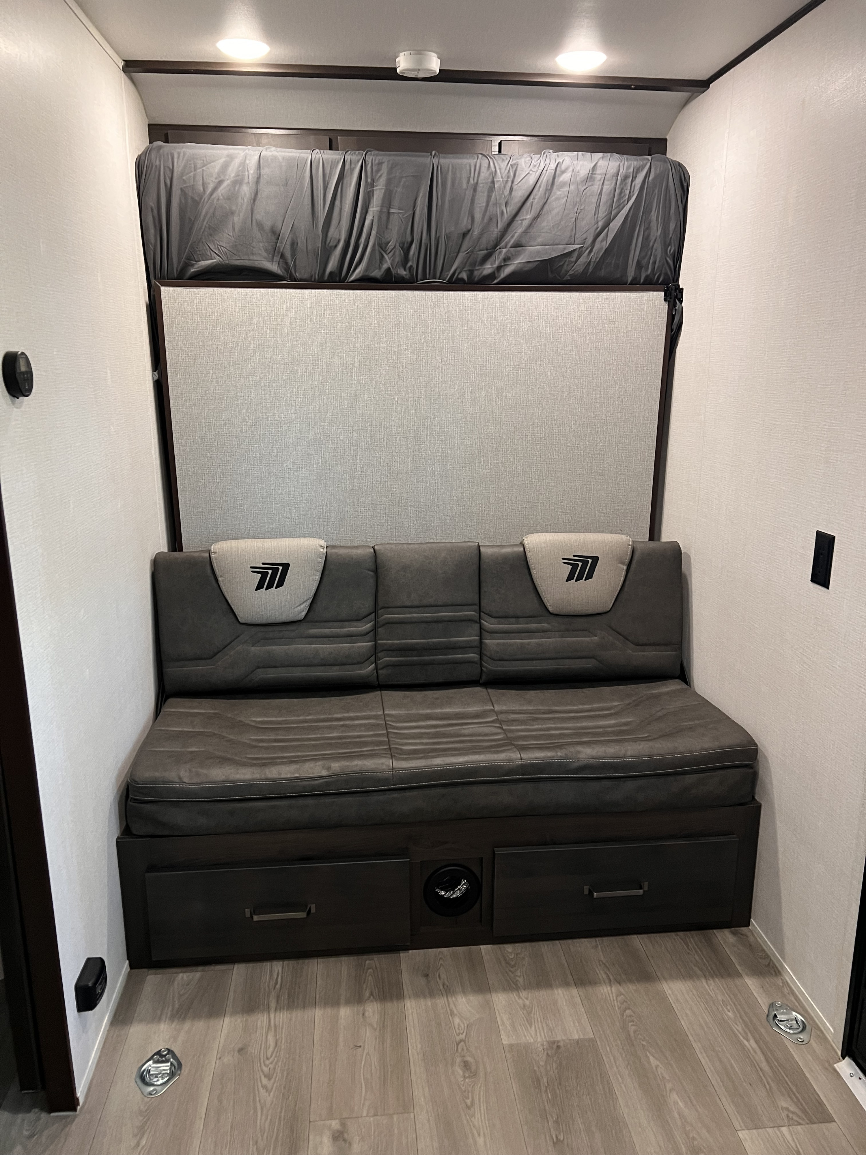 RV rental interior: Sofa, bunk bed, and storage in a modern toy hauler's living/sleeping area.. Grand Design Momentum 2024