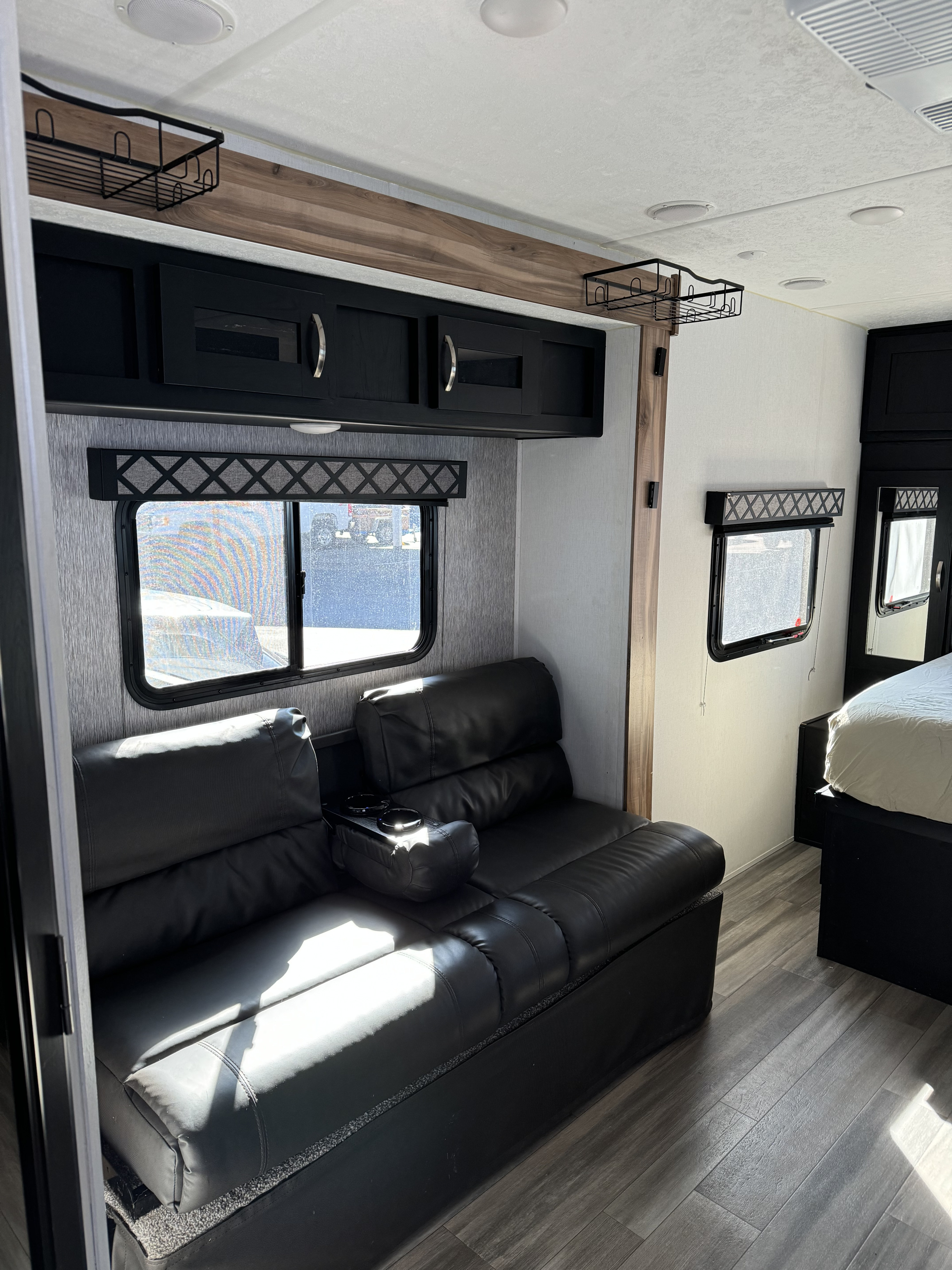 Modern RV rental interior: cozy black leather sofa, sleek overhead cabinets & warm wood accents.. Coachmen Freedom Express Ultra Lite 2022