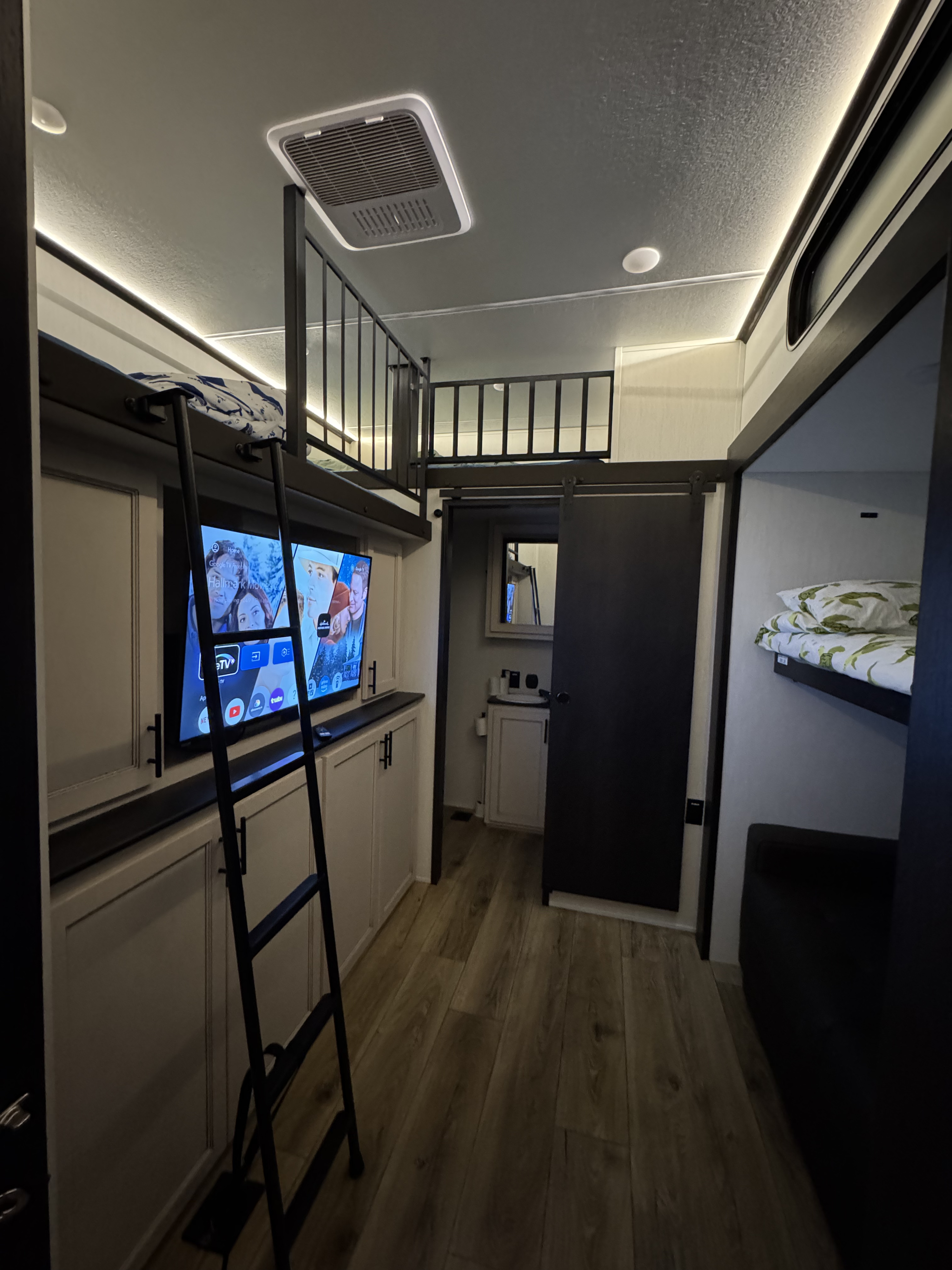 Modern RV rental interior with bunk beds, TV, and accessible bathroom, offering comfortable compact living space.. Forest River Sabre 2025