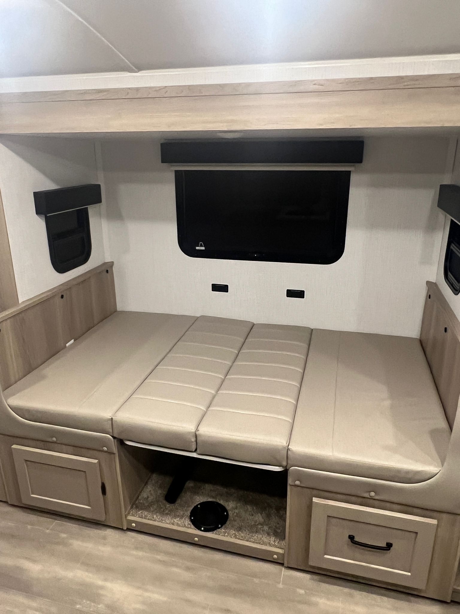RV rental: Beige convertible dinette/bed in a compact RV interior with a wall-mounted TV and under-seat storage.. Forest River Rockwood Geo Pro 2024