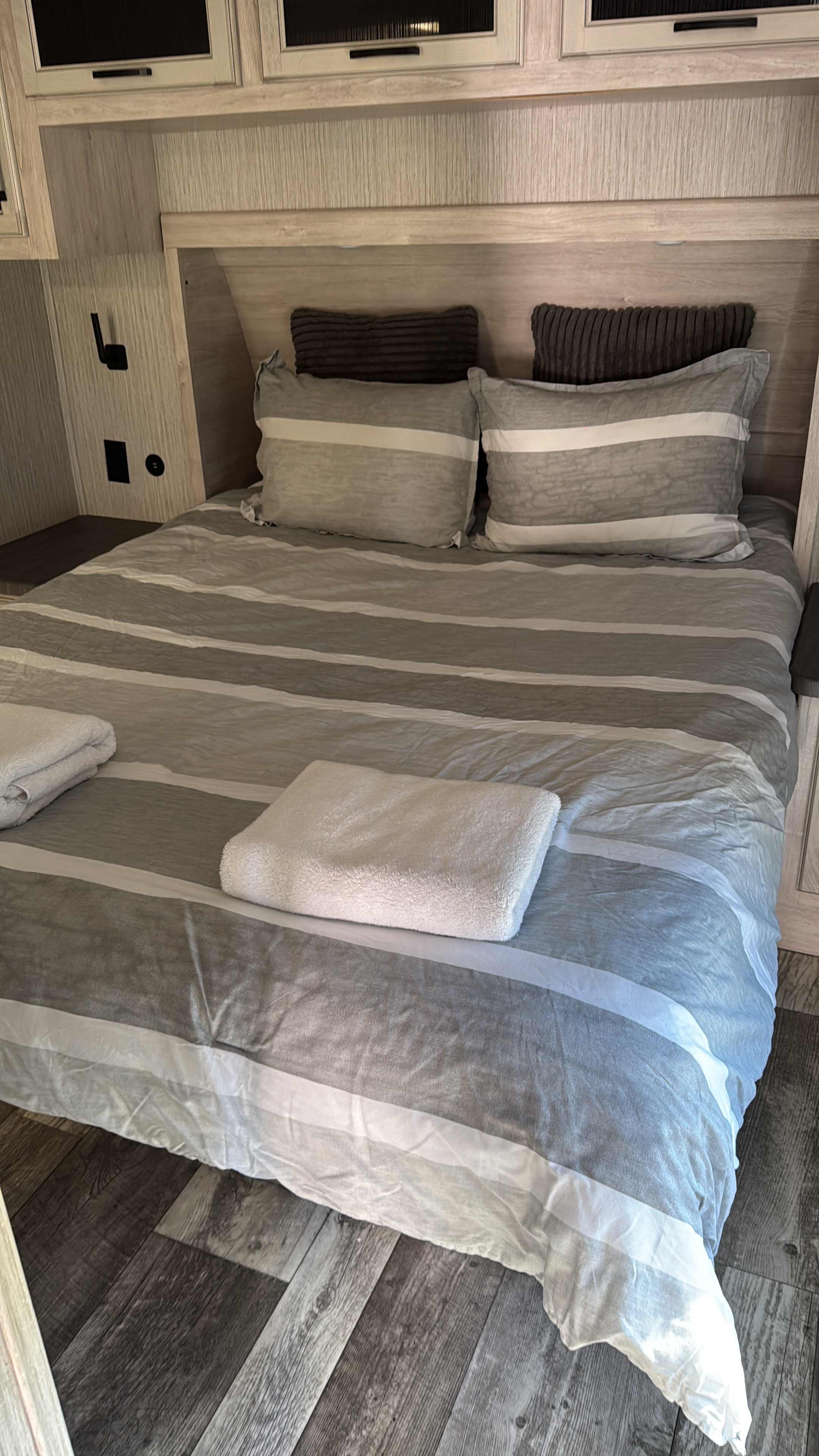 Cozy RV rental bedroom interior featuring striped bedding, pillows, and folded towels on the bed.. Dutchmen Kodiak Ultra Lite 2022