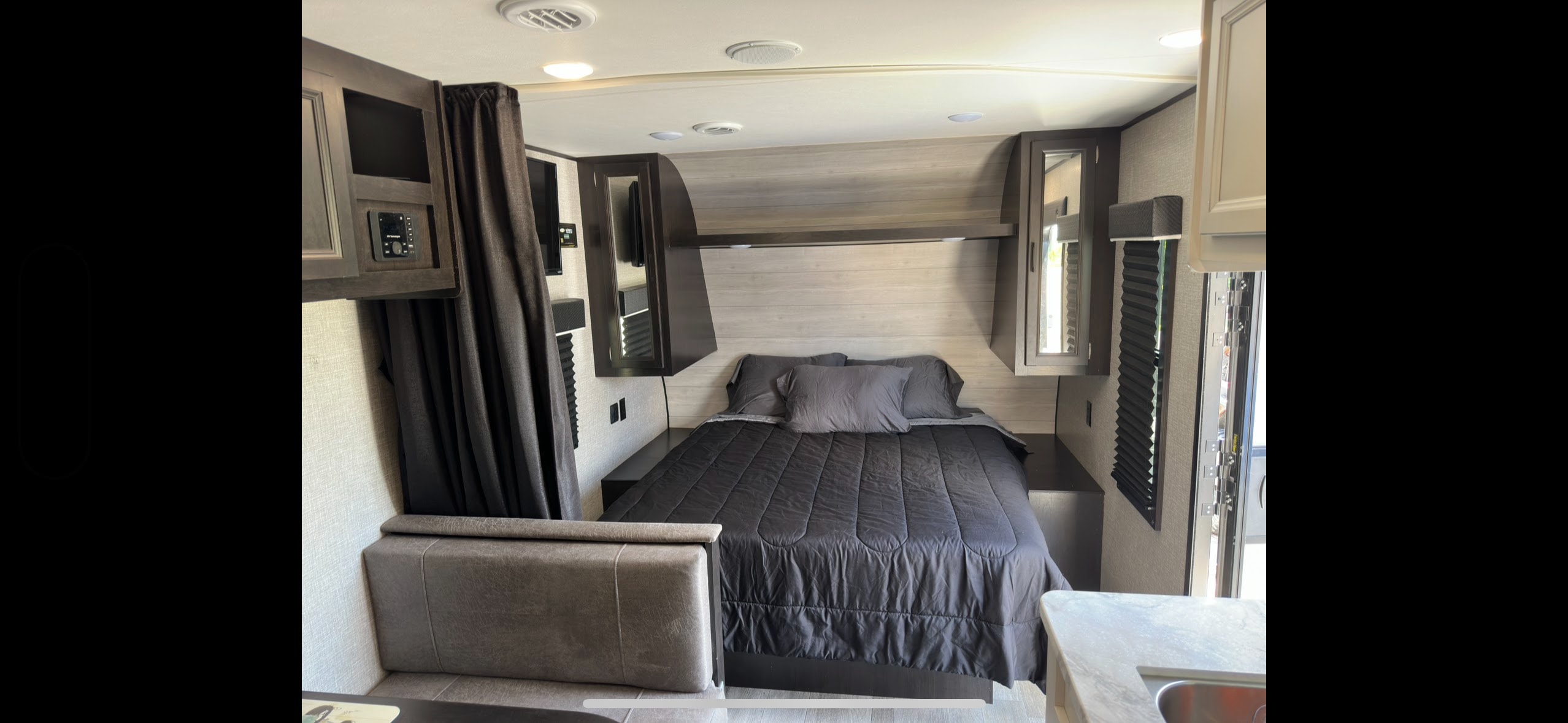 Explore this RV rental's inviting interior: a compact bedroom featuring a comfortable bed, storage, and control panel.. Jayco Jay Flight SLX 2022