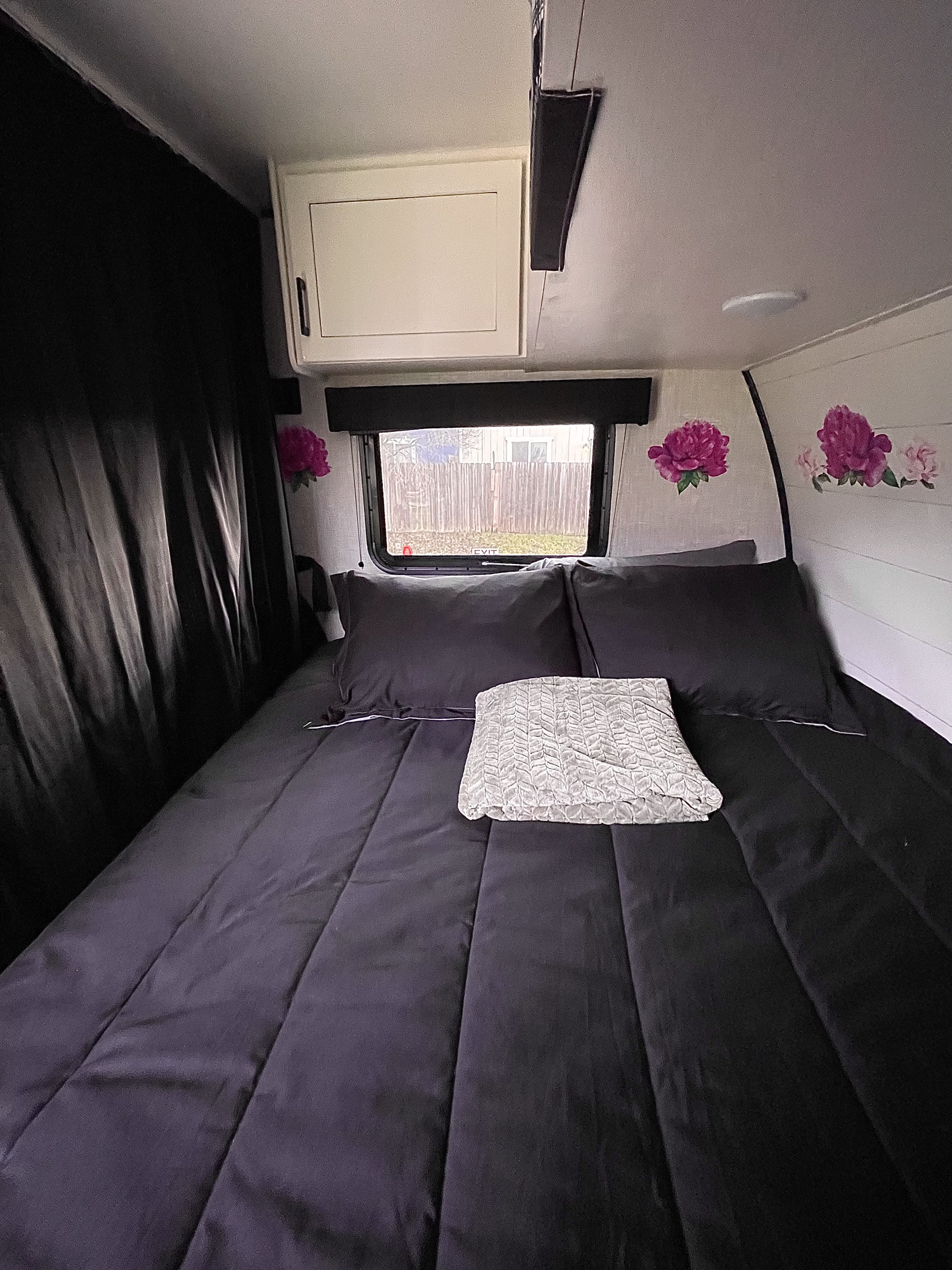 Cozy RV rental bedroom with dark bedding, a window overlooking a fence, and pink floral wall decals.. Jayco Jay flight SLX Baja 175BHW 2025