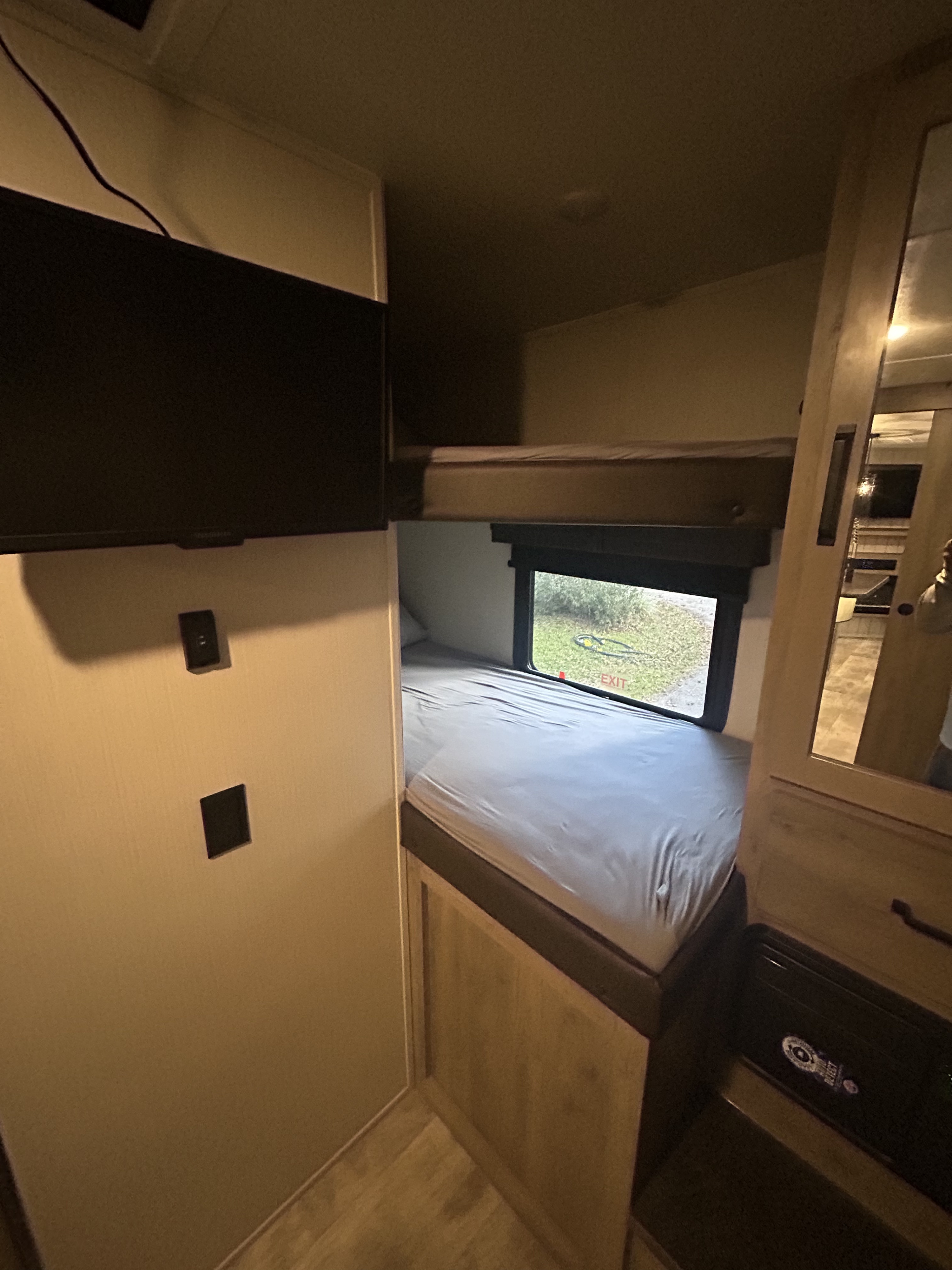 Inside an RV rental: view of bunk beds, a wall-mounted TV, and a window to the outside, ideal for family trips.. Forest River Palomino Puma 2024