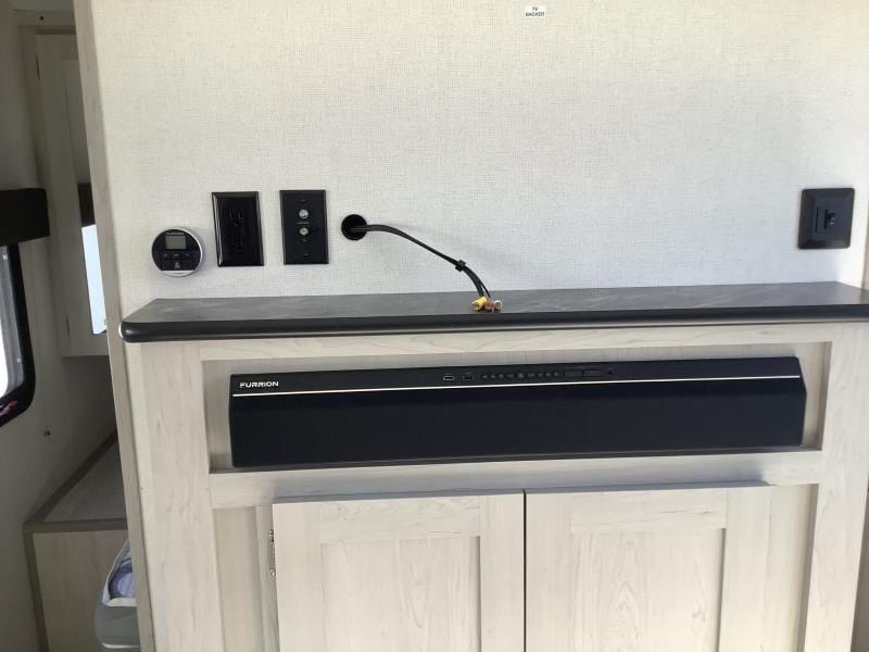 RV rental interior: TV area with Furrion soundbar, power outlets, and a digital climate control panel.. Forest River Tracer LE 2022