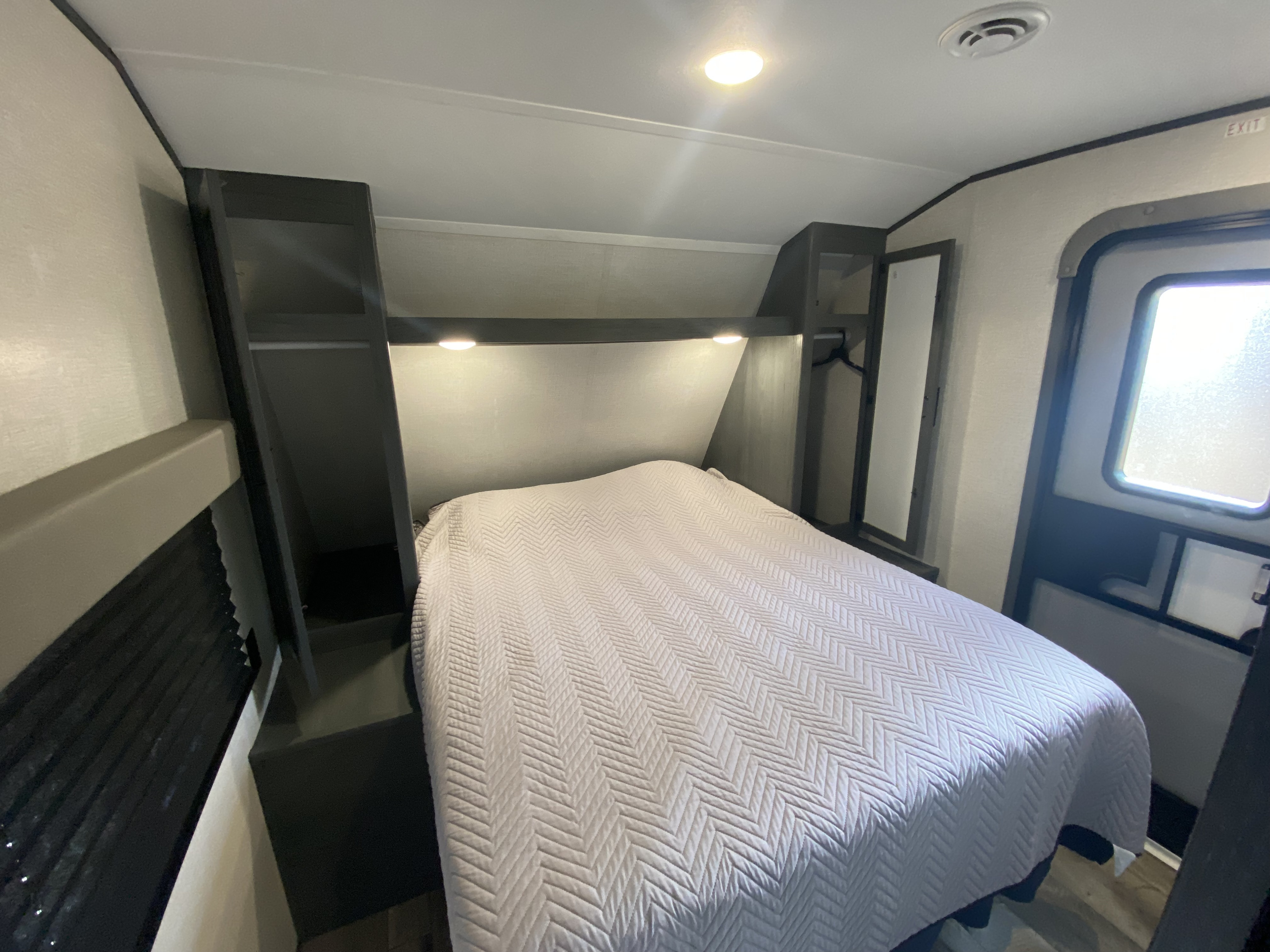 Cozy RV rental bedroom with comfortable bed, integrated storage, and an exit door, perfect for travel.. Dutchmen Aspen Trail 2021