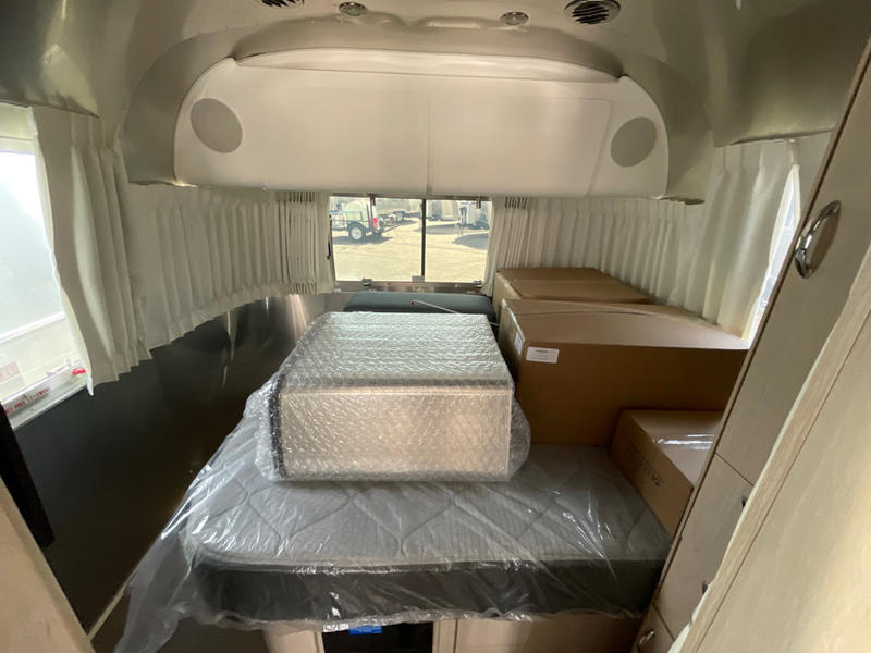 Airstream RV rental interior: new mattress in plastic and boxes. Clean, modern space ready for travel.. Airstream Globetrotter 2024