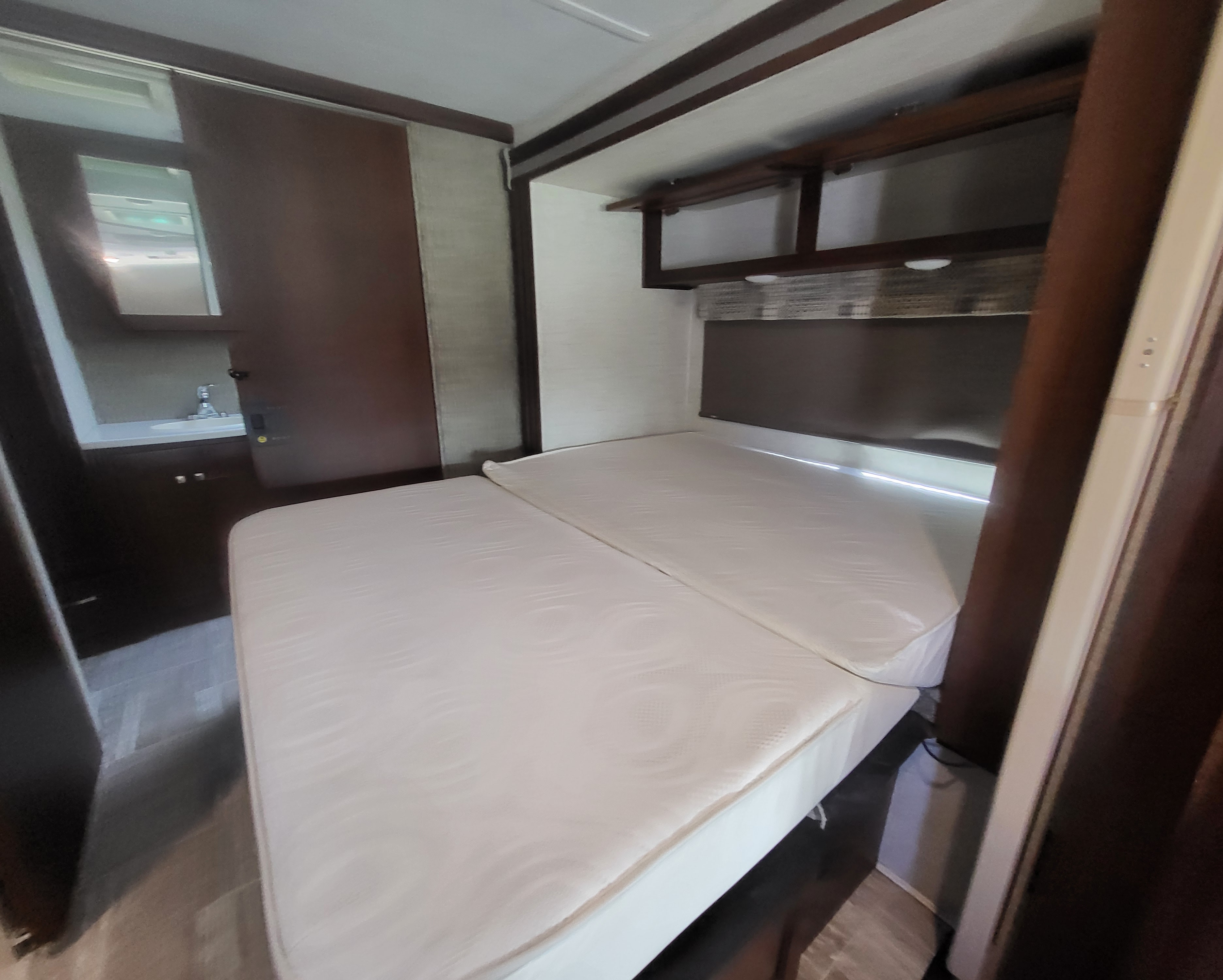 RV rental: Bedroom area with a multi-section white mattress, overhead cabinets, and a visible vanity/sink. Compact RV interior.. Forester Forester Motorhome 2019